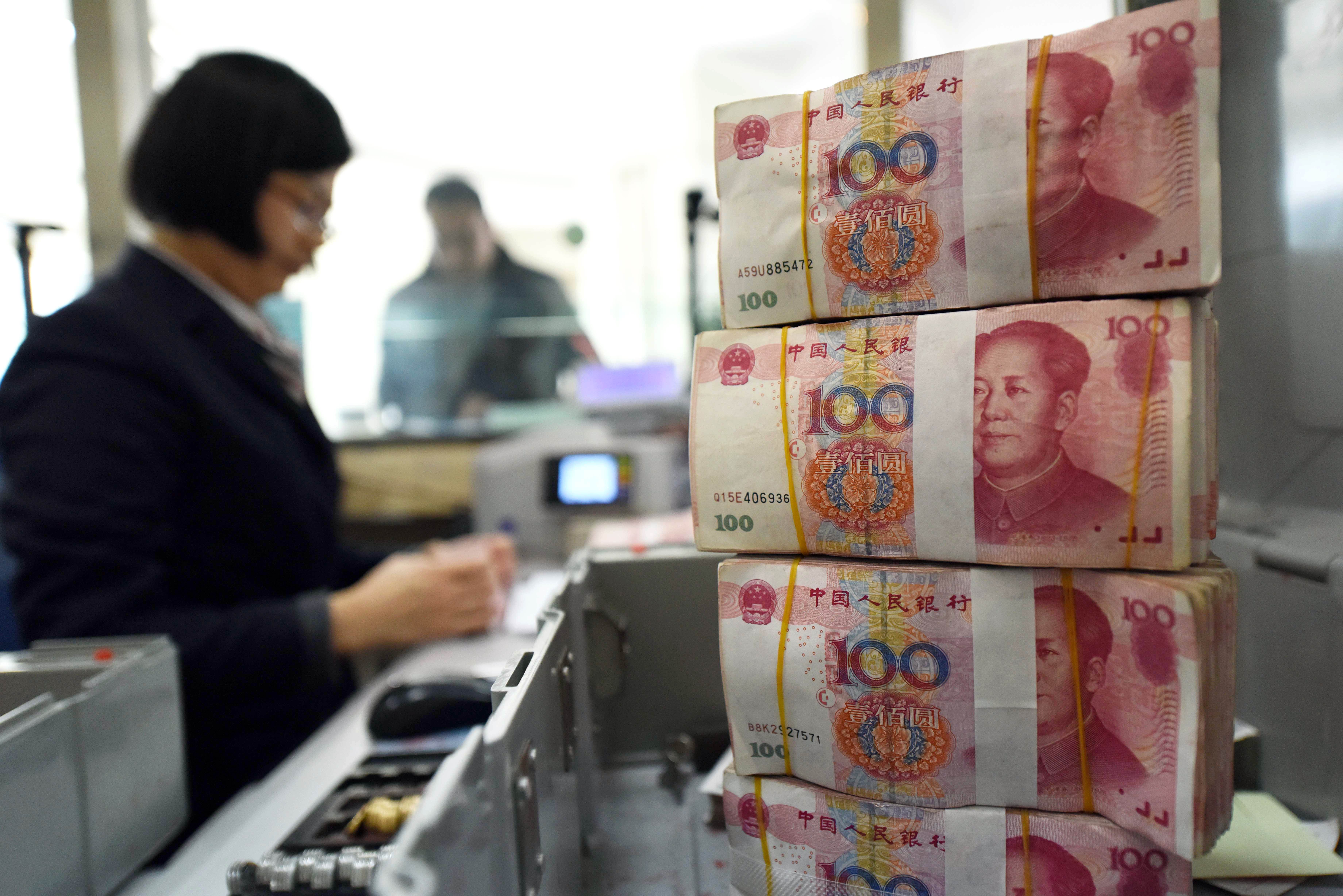 An employee counts 100-yuan (15 USD) banknotes at a bank in Lianyungang, in eastern China's Jiangsu province on January 7, 2016. China weakened the value of its yuan currency by 0.51 percent to 6.5646 against the US dollar on January 7, figures from the China Foreign Exchange Trade System showed. CHINA OUT AFP PHOTO