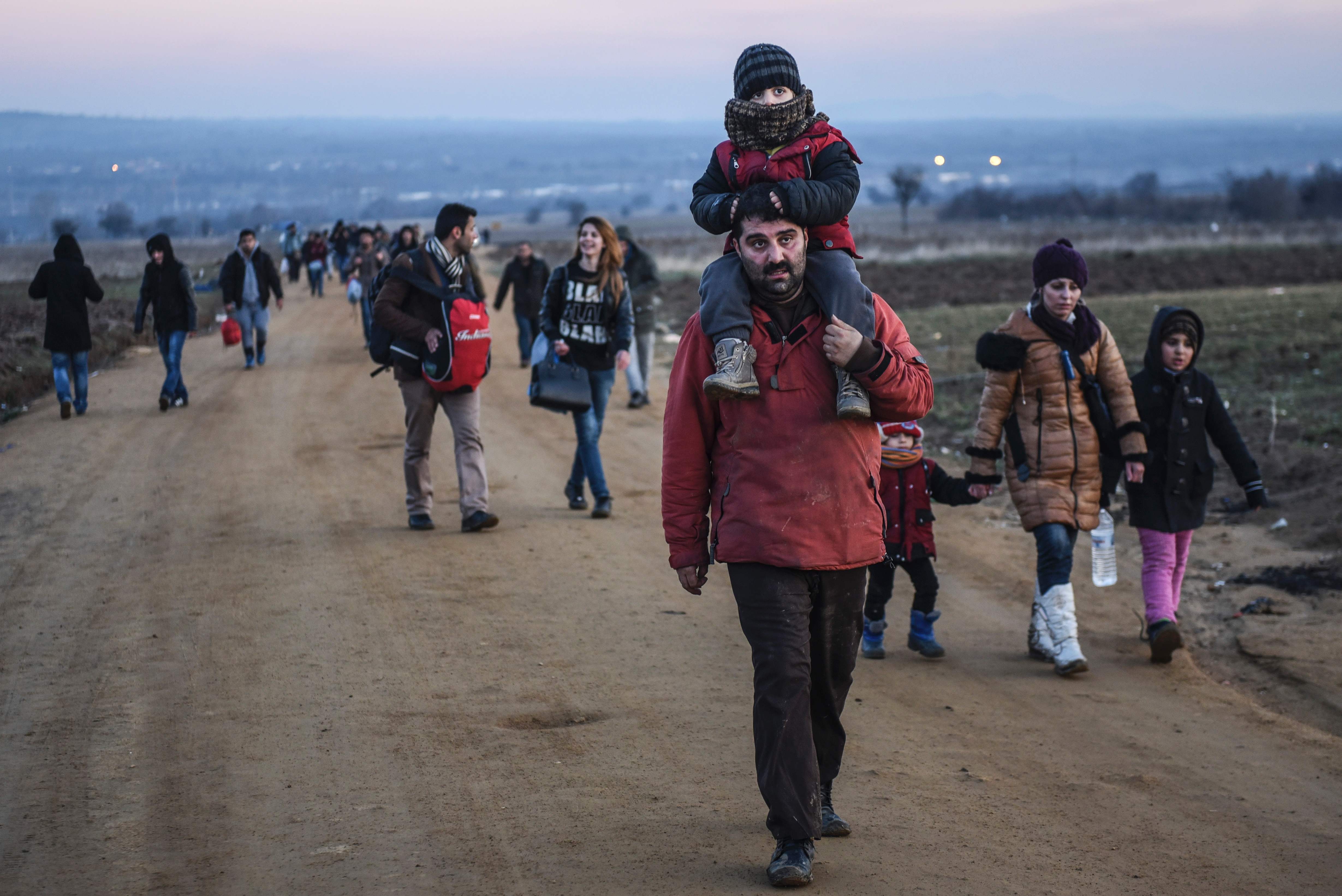 Migrants and refugees walk on a road after crossing the Macedonian border into Serbia, near the village of Miratovac, on January 8, 2016. More than a million refugees and migrants arrived in Europe in 2015 in the worst crisis of its kind to face the continent since World War II. / AFP / ARMEND NIMANI