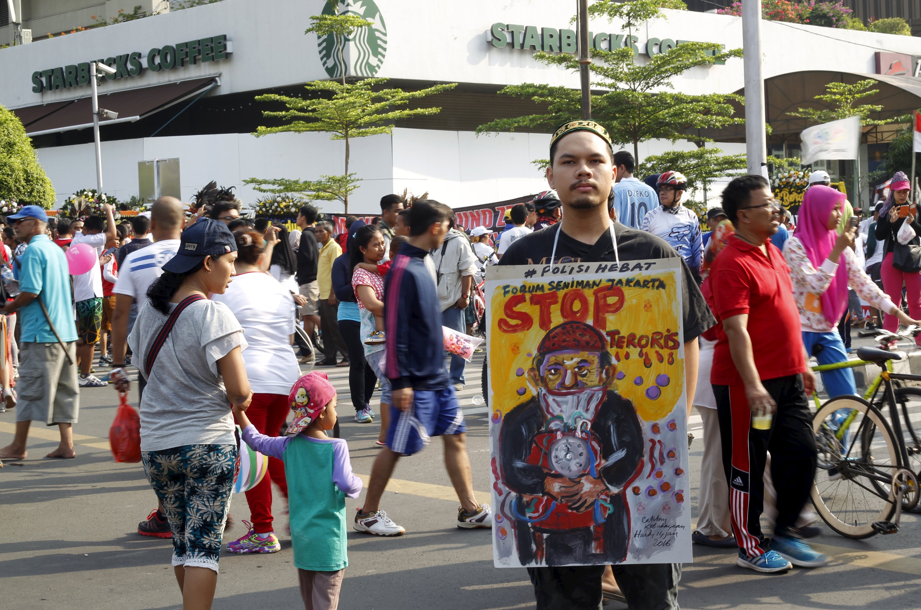 A man holds a placard that reads "Stop terrorists" during the "car free" period at the site of this week's militant attack in central Jakarta, Indonesia, January 17, 2016. Indonesian police on Saturday named the five men they suspect launched this week's gun and bomb attack in Jakarta, which was claimed by Islamic State, and said they had arrested 12 people linked to the plot who planned to strike other cities. REUTERS/Garry Lotulung EDITORIAL USE ONLY. NO RESALES. NO ARCHIVE