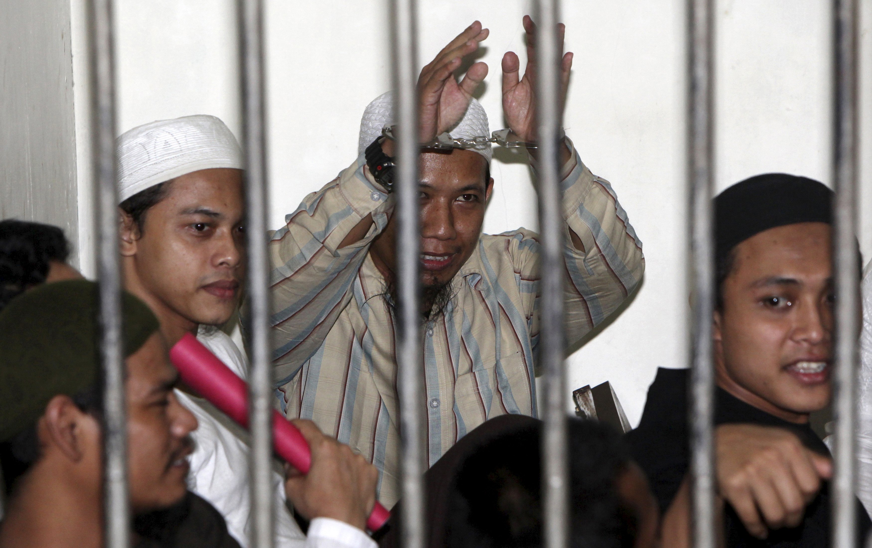Radical Muslim cleric Aman Abdurrahman (C), also known as Oman Rochman, raises his hands in a holding cell as he waits with other militants for their trial in Jakarta, in this August 26, 2010 file photo. From behind bars, Abdurrahman heads an umbrella organisation formed in 2015 through an alliance of splinter groups that support Islamic State. REUTERS/Dadang Tri/Files