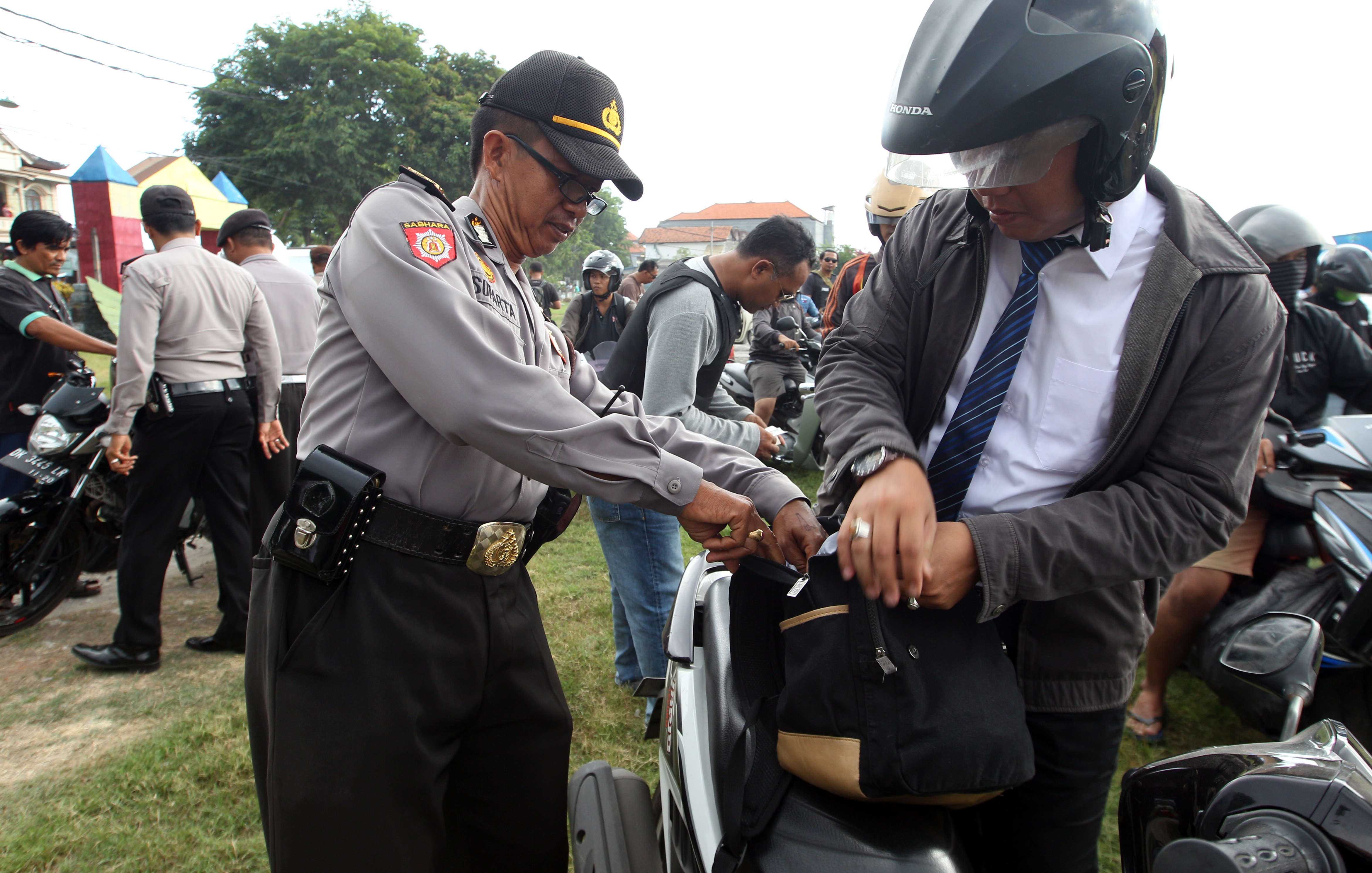 Police officers checked motorcyclists at a security check point in Bali, Indonesia, Wednesday, Jan. 20, 2016. Security at resort island of Bali has been increased after the Jakarta attack, which was the first major assault by militants in Indonesia since 2009. (AP Photo/Firdia Lisnawati)