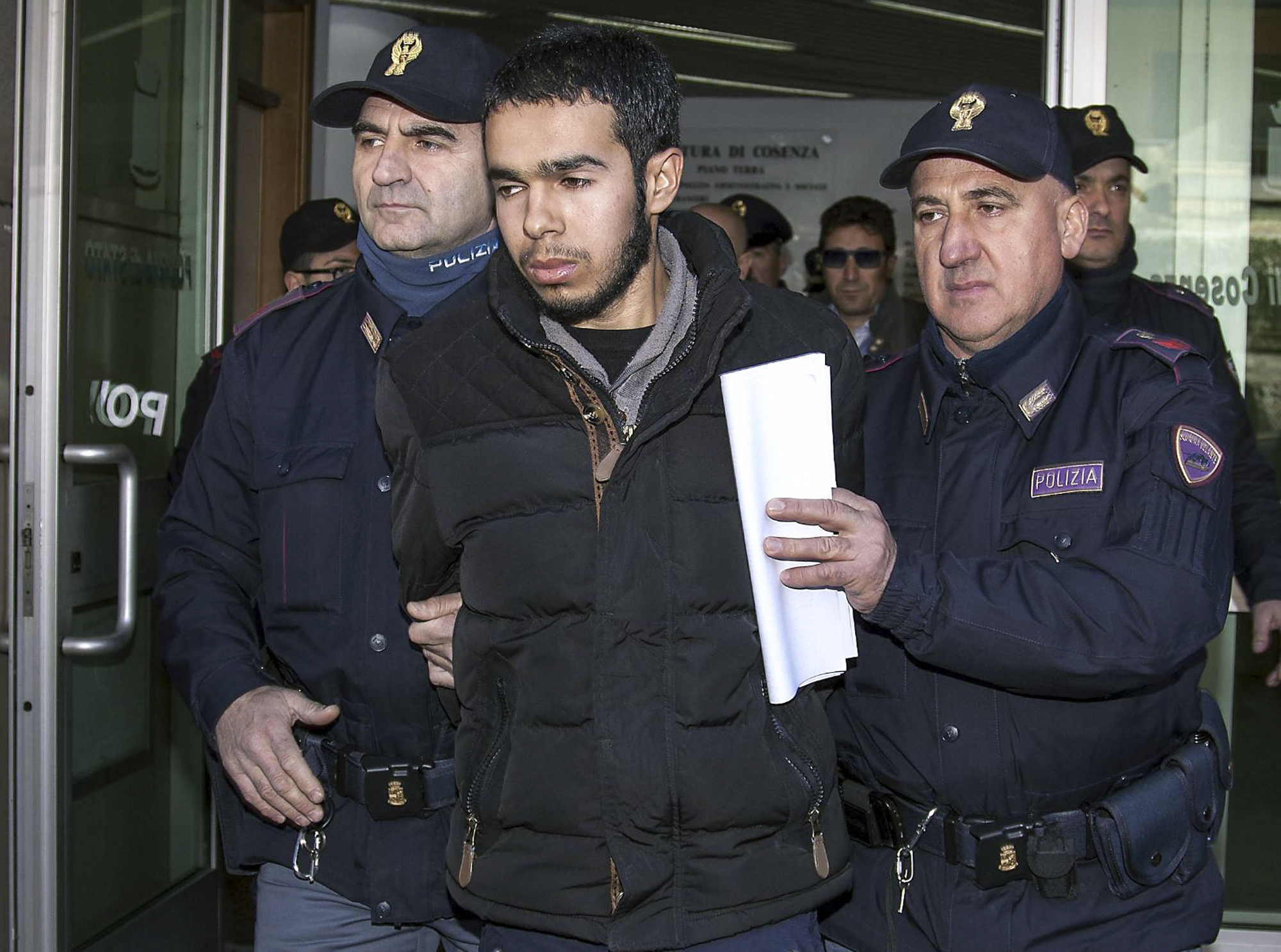 Mehdi Hami, center, is escorted by two officers as he leaves Cosenza's Police headquarters, Italy, Monday, Jan. 25, 2016. Italian authorities have arrested a Moroccan citizen living in southern Italy suspected of seeking to train as a foreign fighter for Islamic State. Italian police said in a statement that they arrested 25-year-old Mehdi Hamil who had been under investigation since July when he was stopped at Rome's international airport after being refused entry to Turkey. (Francesco Arena/ANSA via AP)