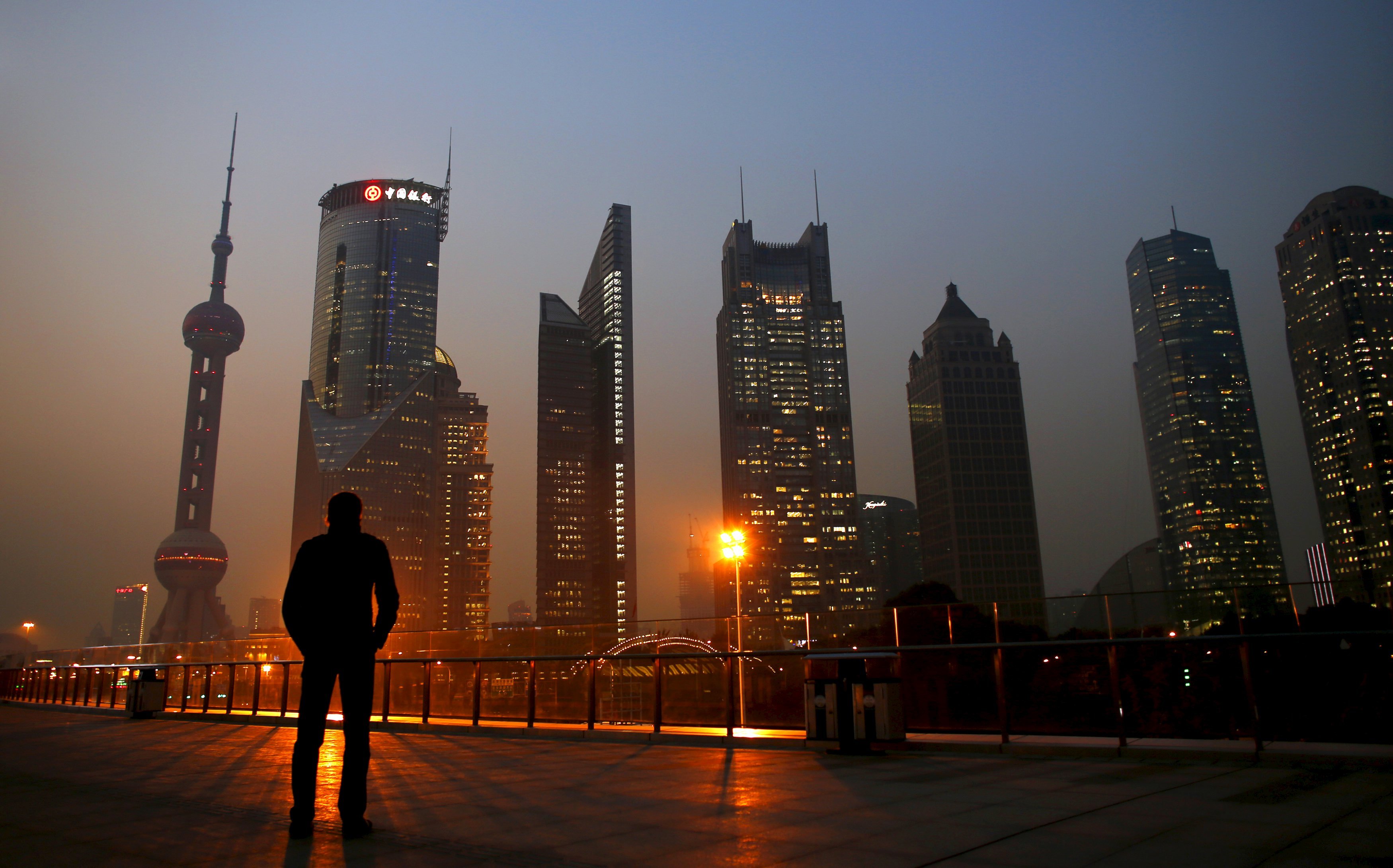 A man looks at the Pudong financial district of Shanghai in this November 20, 2013 file photo. As China's economy registers its slowest growth in a quarter century, more borrowers are in default, swamping banks in a rising tide of non-performing loans (NPLs). REUTERS/Carlos Barria/Files