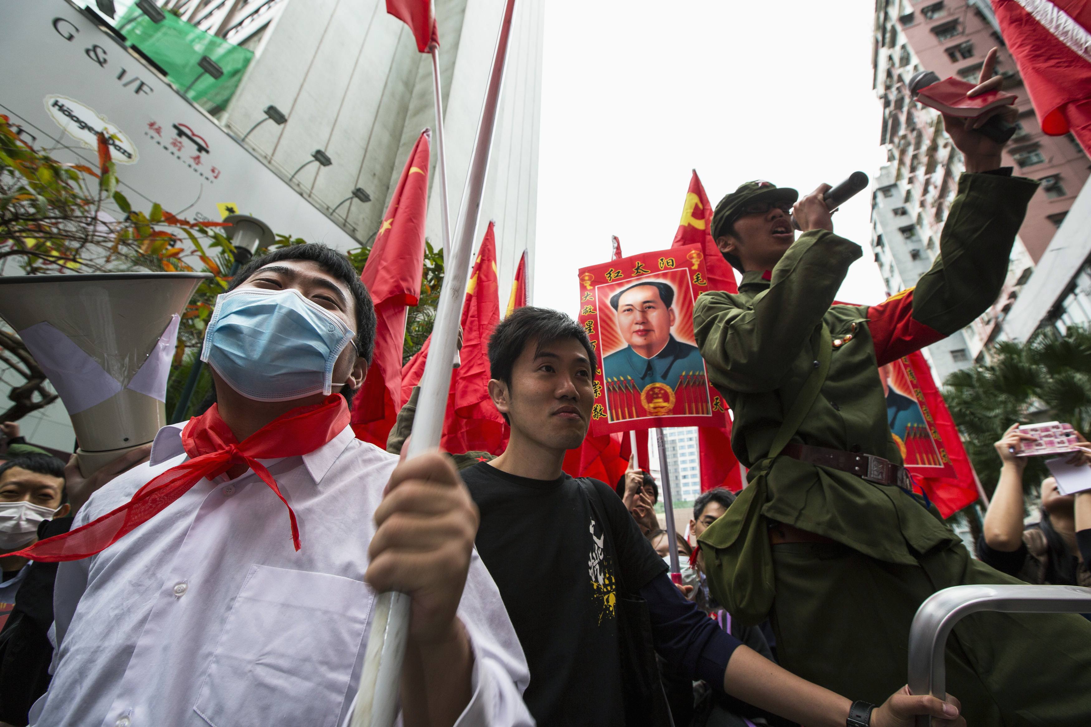 Protesters hold Chinese national flags and a picture of late Chinese Communist Party leader Mao Zedong during an anti-mainland tourist rally in Hong Kong's famous Mong Kok shopping district March 9, 2014. Hundreds of protesters joined a rally organized by an anti-mainland group in Mong Kok, mocking and dissuading mainland Chinese shoppers from buying imported daily essentials in Hong Kong. The protesters claim that prices of imported daily essentials have gone up and supply is limited, according to local media. REUTERS/Tyrone Siu (CHINA - Tags: POLITICS BUSINESS CIVIL UNREST TRAVEL)