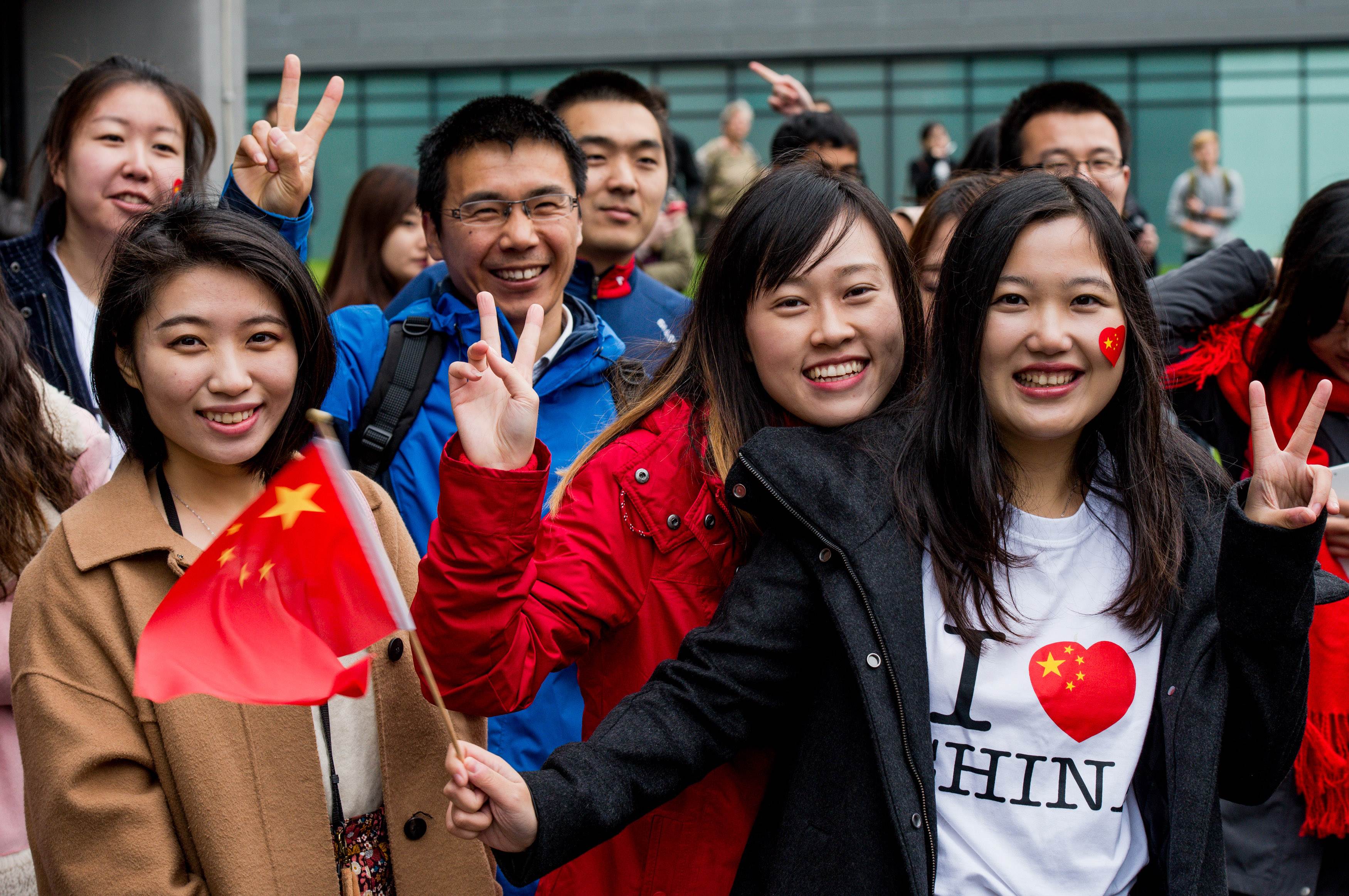 Chinese students show support for Chinese President Xi Jinping as he arrives to tour the National Graphene Institute at Manchester University with Britain's Chancellor of the Exchequer George Osborne on October 23, 2015 in Manchester, north west England. Chinese President Xi Jinping blew the final whistle on his state visit to Britain today with a day out at the English Premier League leaders Manchester City. AFP PHOTO / POOL / Richard Stonehouse