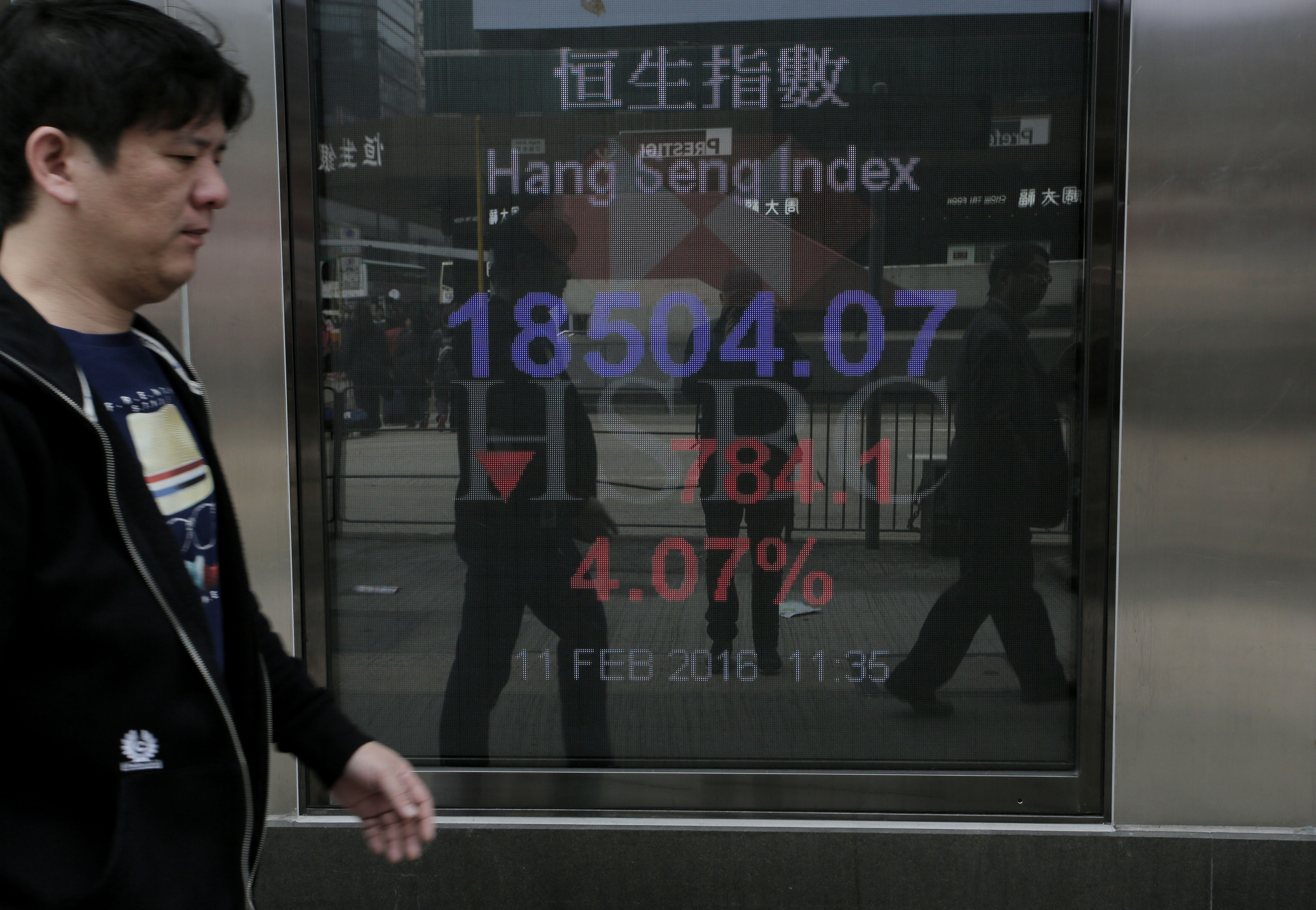 A man walk past a bank electronic board showing the Hong Kong share index at Hong Kong Stock Exchange, Thursday, Feb. 11, 2015. Hong Kong's stocks are set for their biggest daily drop in six months on Thursday, as worries about the health of the global economy, particularly the mainland, sparked a sell-off in financials and energy shares, according to government radio. (AP Photo/Vincent Yu)