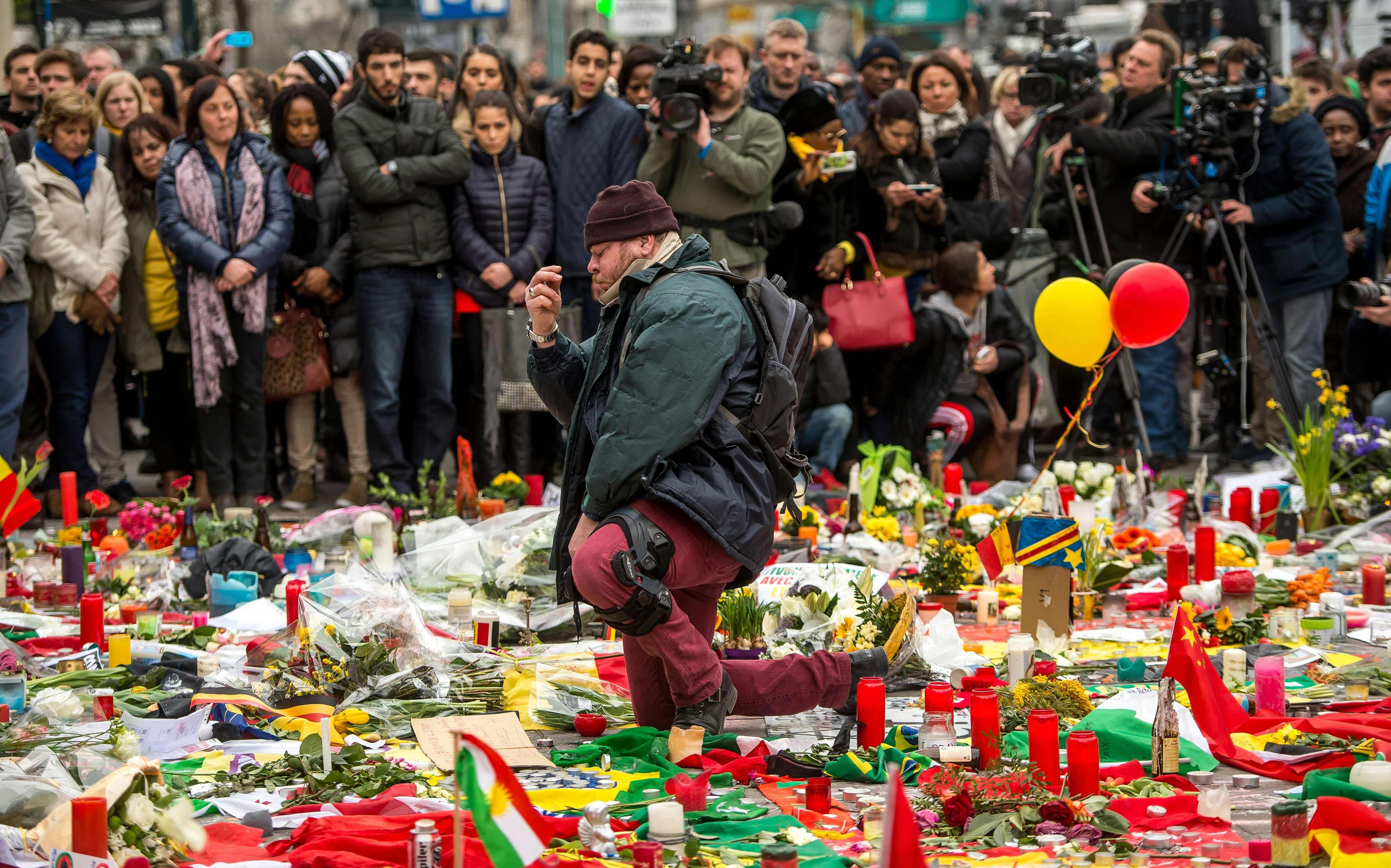 A man makes the sign of the cross during a minute of silence held at a makeshift memorial in front of the Brussels stock exchange on Place de la Bourse, two days after a triple bomb attack in the city. Photo: AFP
