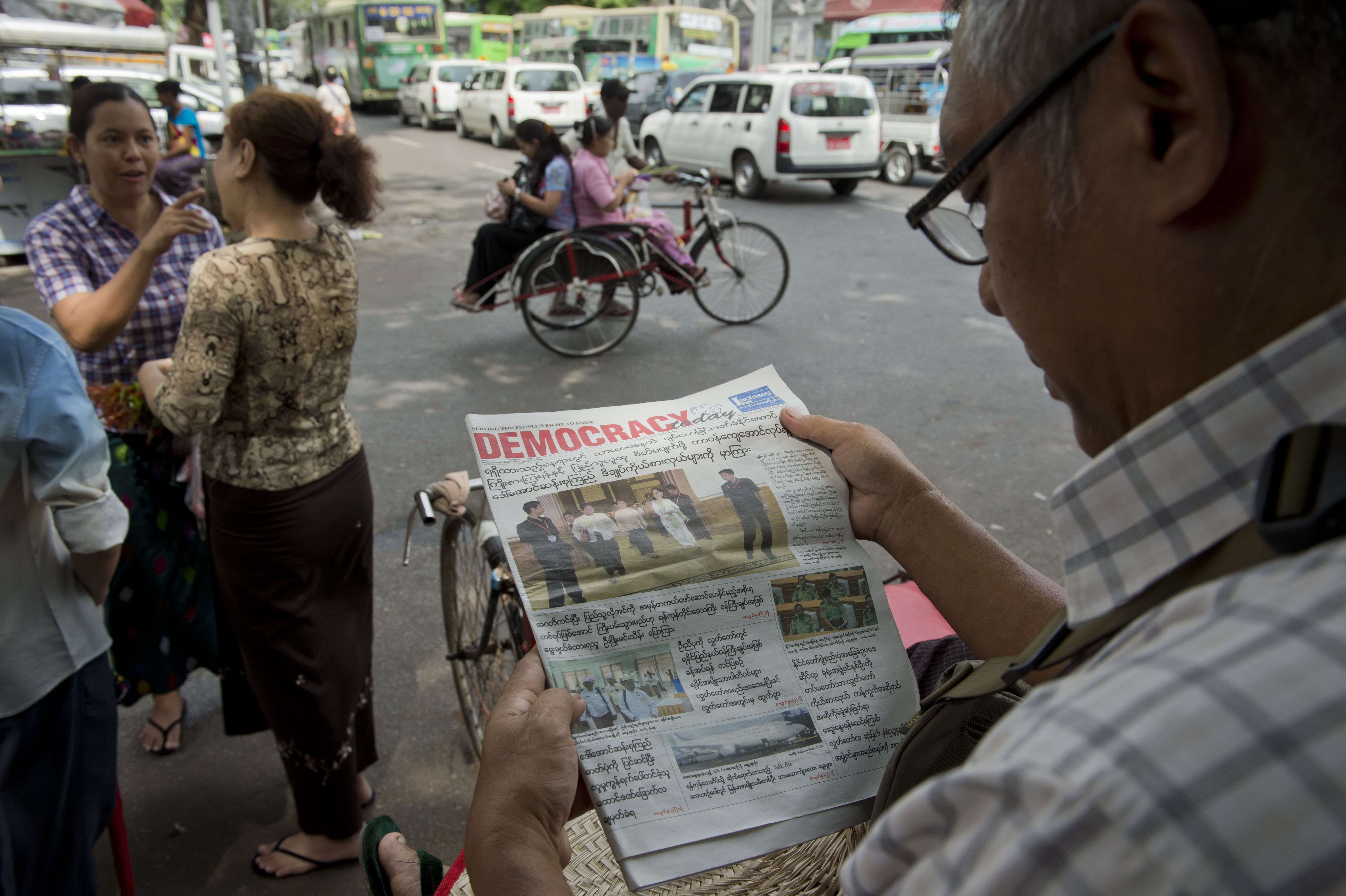 A Myanmar man reads a newspaper reporting on the handover of government in Yangon, a day before a new civilian government overseen by democracy icon Aung San Suu Kyi took office. Photo: AFP