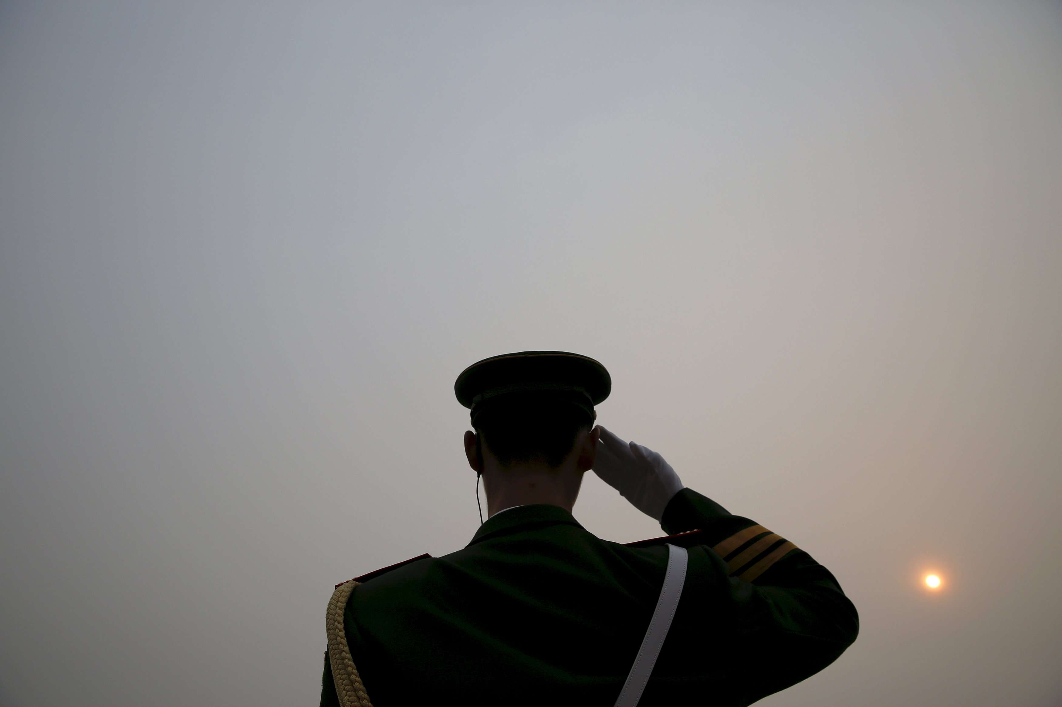 The sun appears through thick smog as a paramilitary policeman salutes delegates arriving at the Great Hall of the People before the opening ceremony of the National People's Congress in Beijing this year. Photo: Reuters
