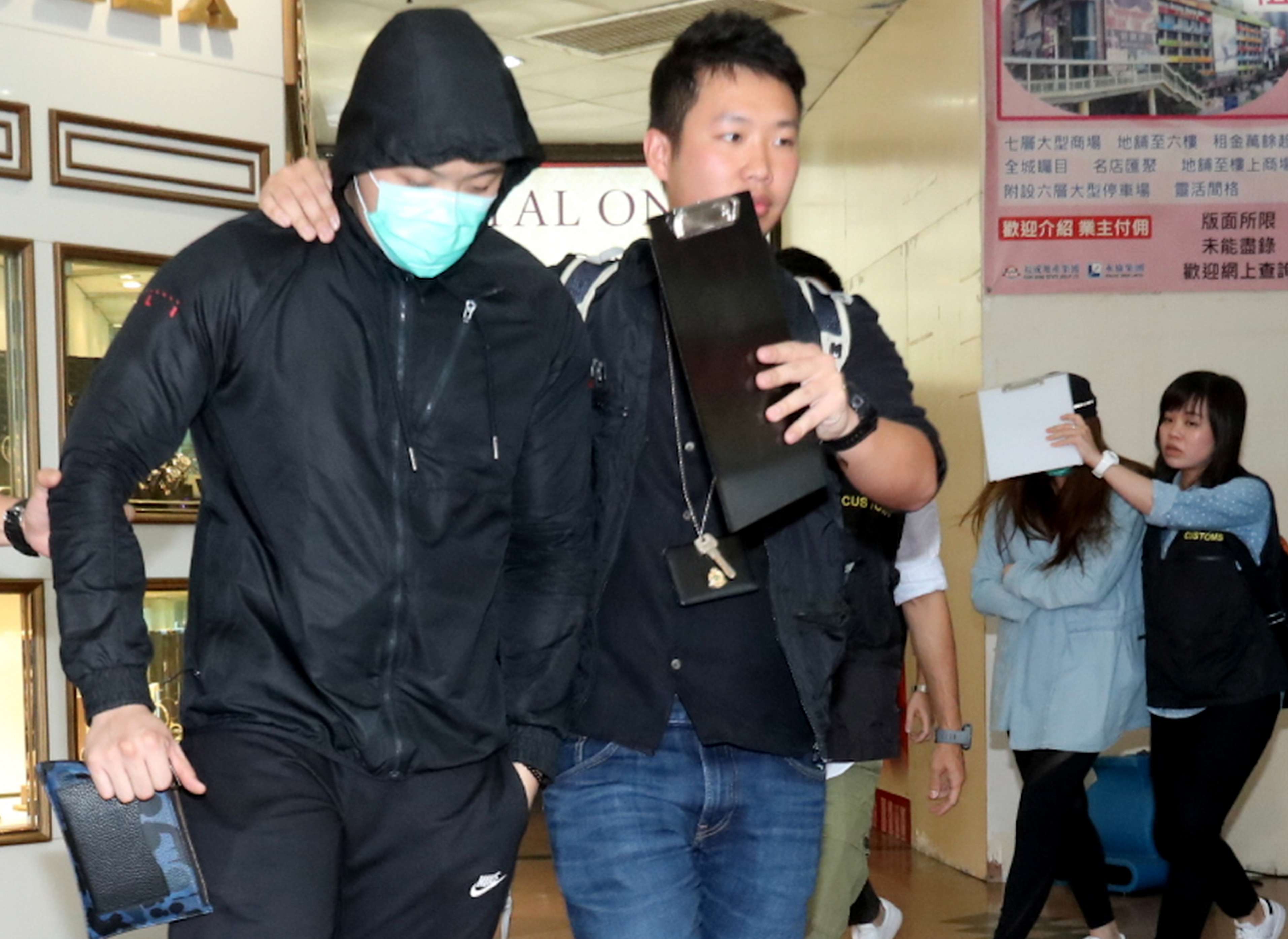 A Customs officer lead a worker from the gym. Photo: SCMP Pictures