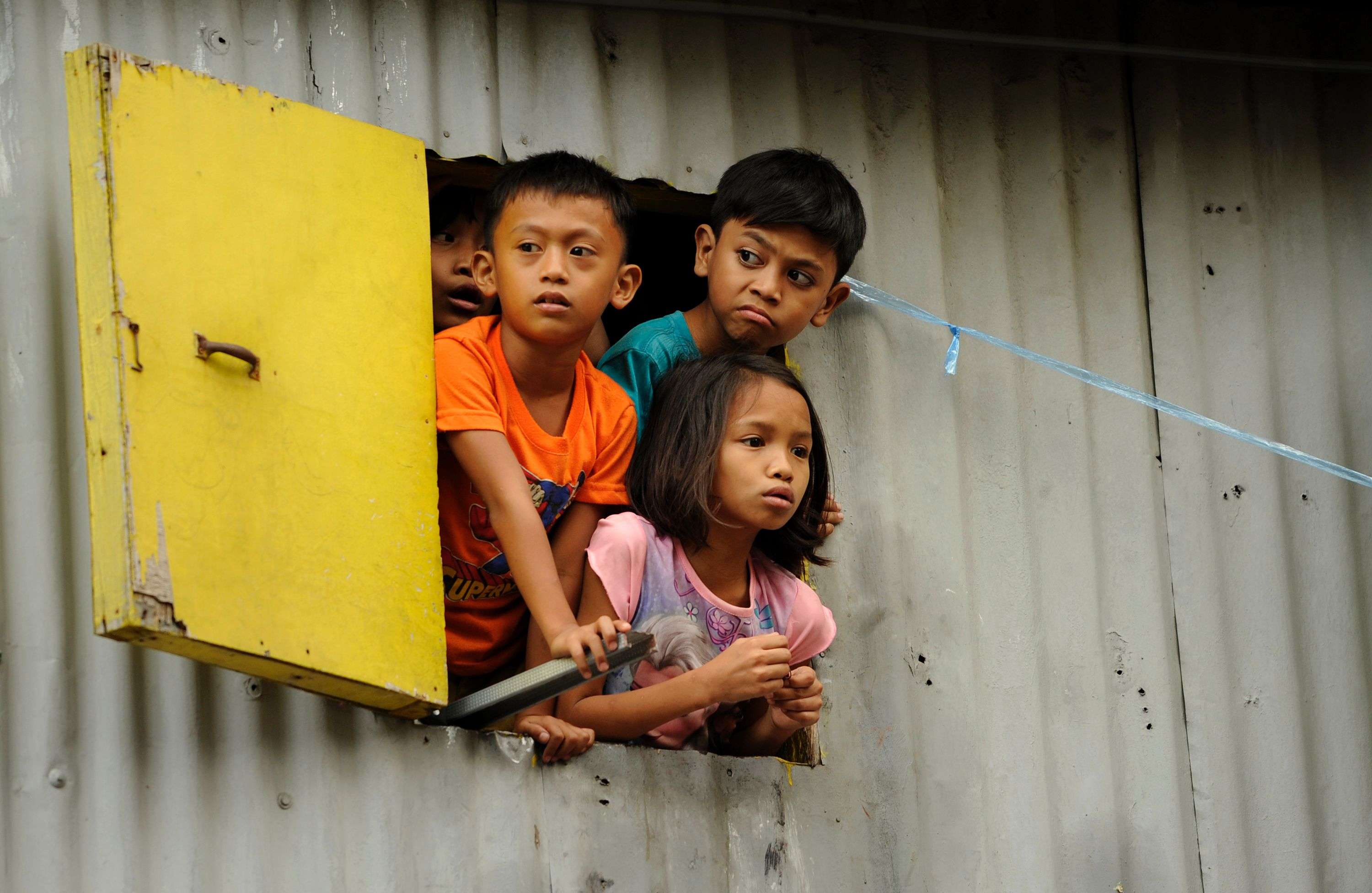 Children look out of a window in a shanty town in Manila. A third of all Asians live in extreme poverty, according to the Asian Development Bank. Photo: AFP