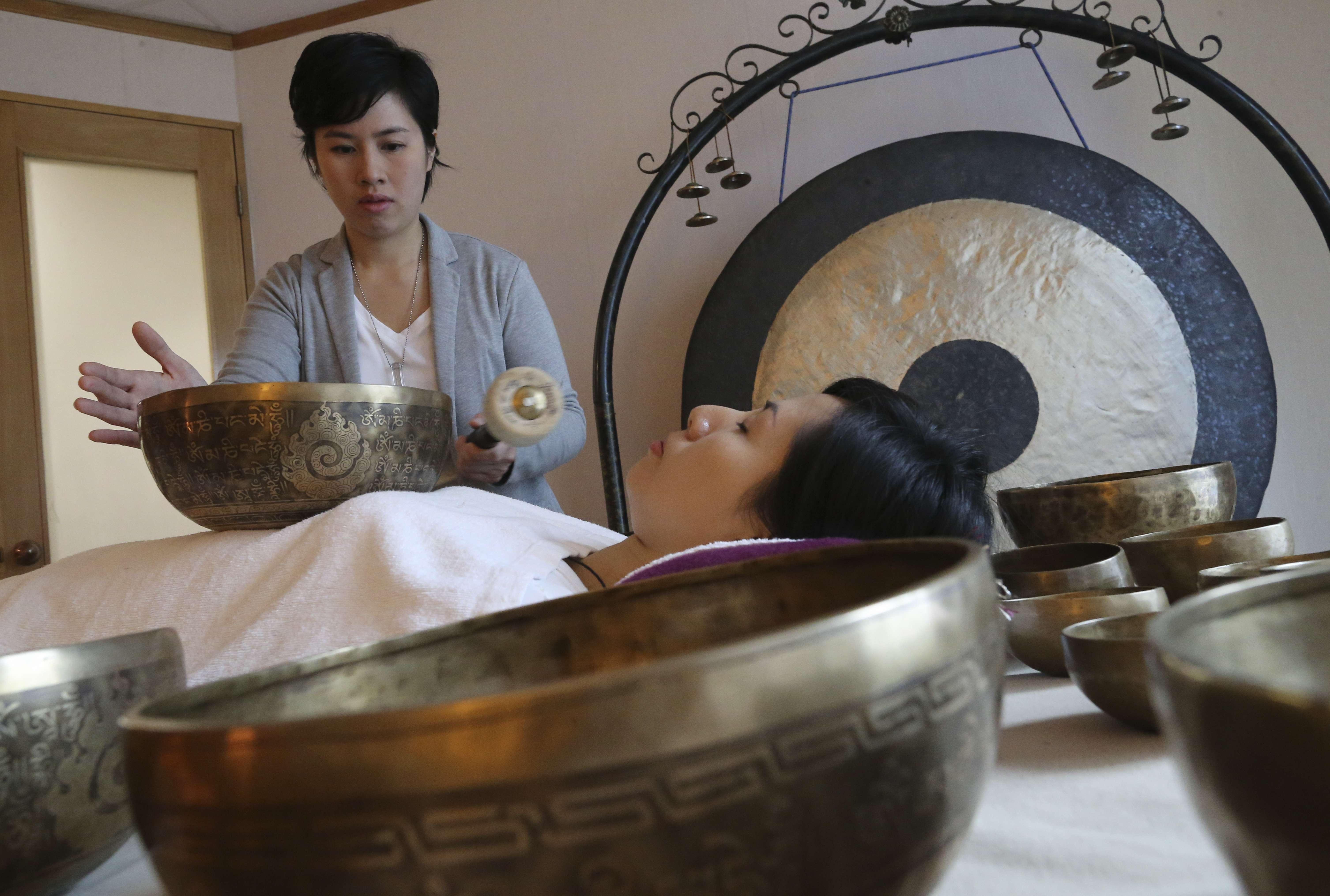 Jasmine Hui (standing) and Jennifer Tang (lying down), founders of Sound Therapy, demonstrate the singing bowls at their Wan Chai centre. Photo: Dickson Lee
