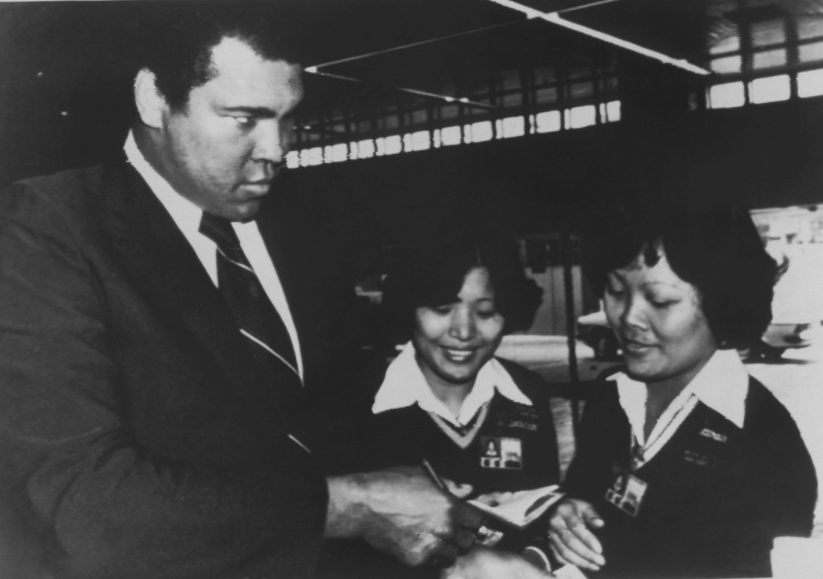 Muhammad Ali playfully glares at two women security guards as they check his travel documents at Hong Kong’s Kai Tak airport in December 1979 while on his way to mainland China. Photo: AP