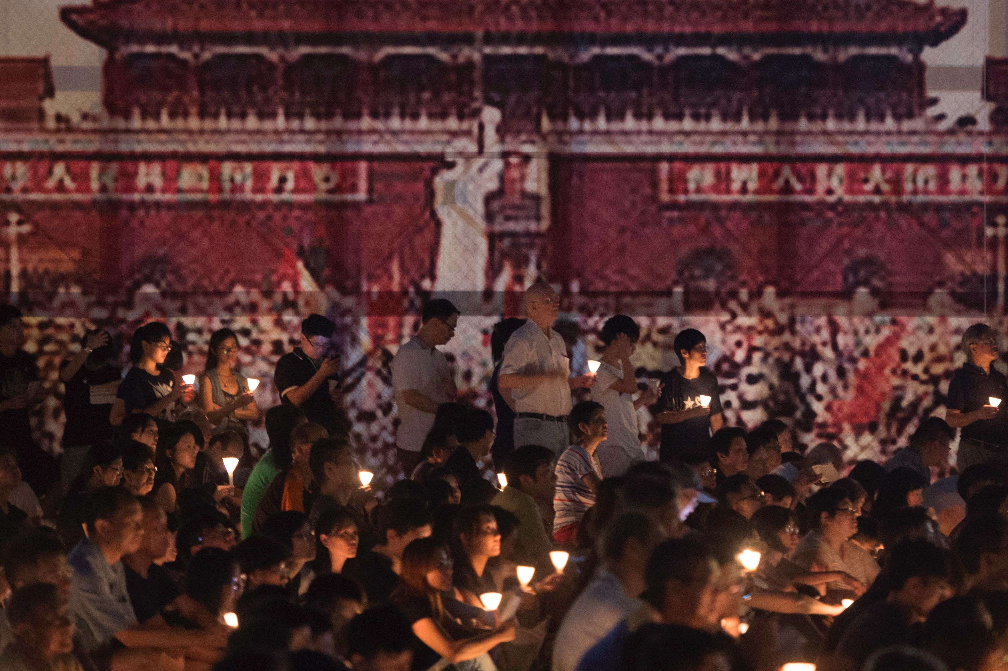 Participants hold candles during a vigil in Victoria Park, Hong Kong, for the 27th anniversary of the Tiananmen Square crackdown, in front of a large banner showing the Beijing demonstrations. Many of those who attended nurse hopes for a democratic China. Photo: AFP