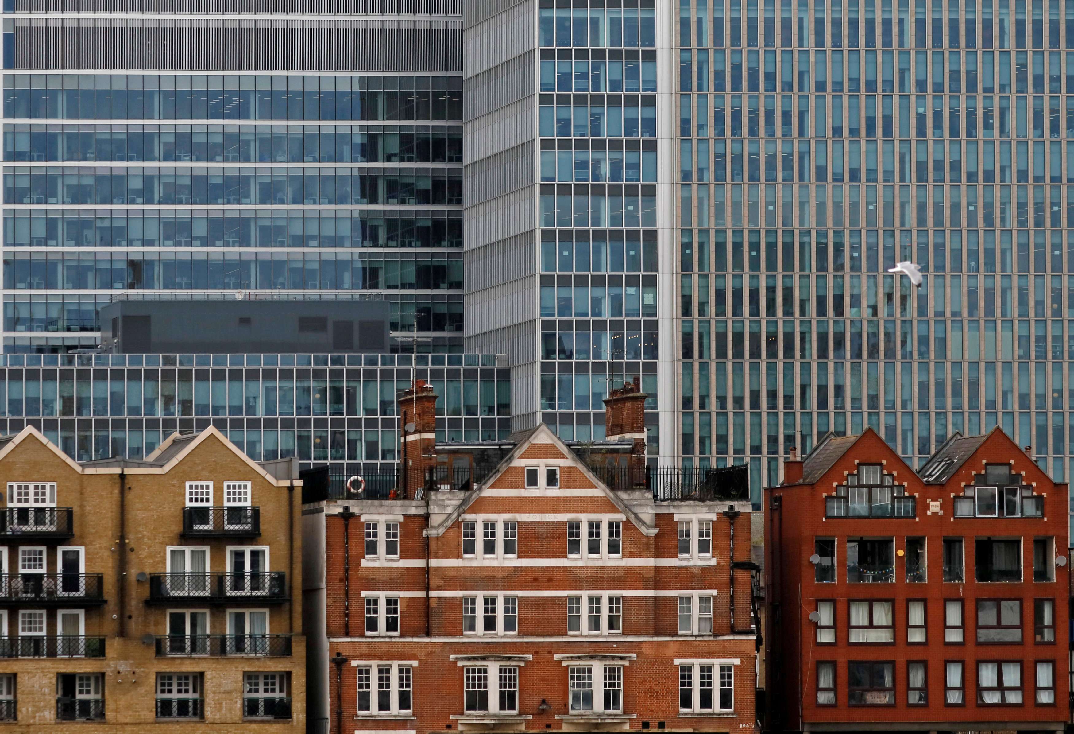 Long office leases seen protecting investors from short-term fluctuations. Photo: Reuters Apartment buildings are backdropped by skyscrapers of banks at Canary Wharf in London, Britain October 30, 2015. REUTERS/Reinhard Krause/File Photo