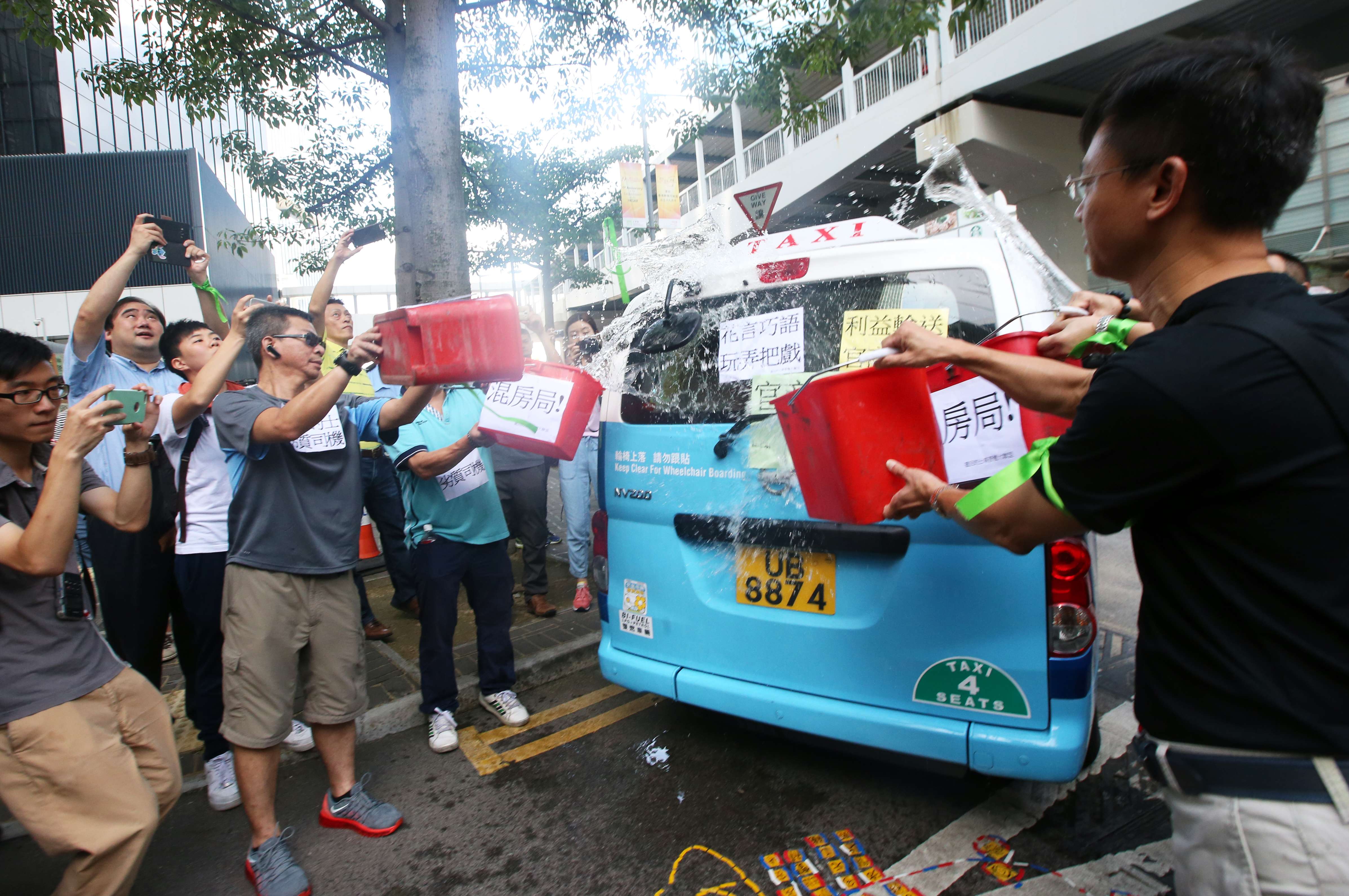 Protesters at Tamar pouring water over a model of taxi that would be used in the government’s plan. Photo: David Wong