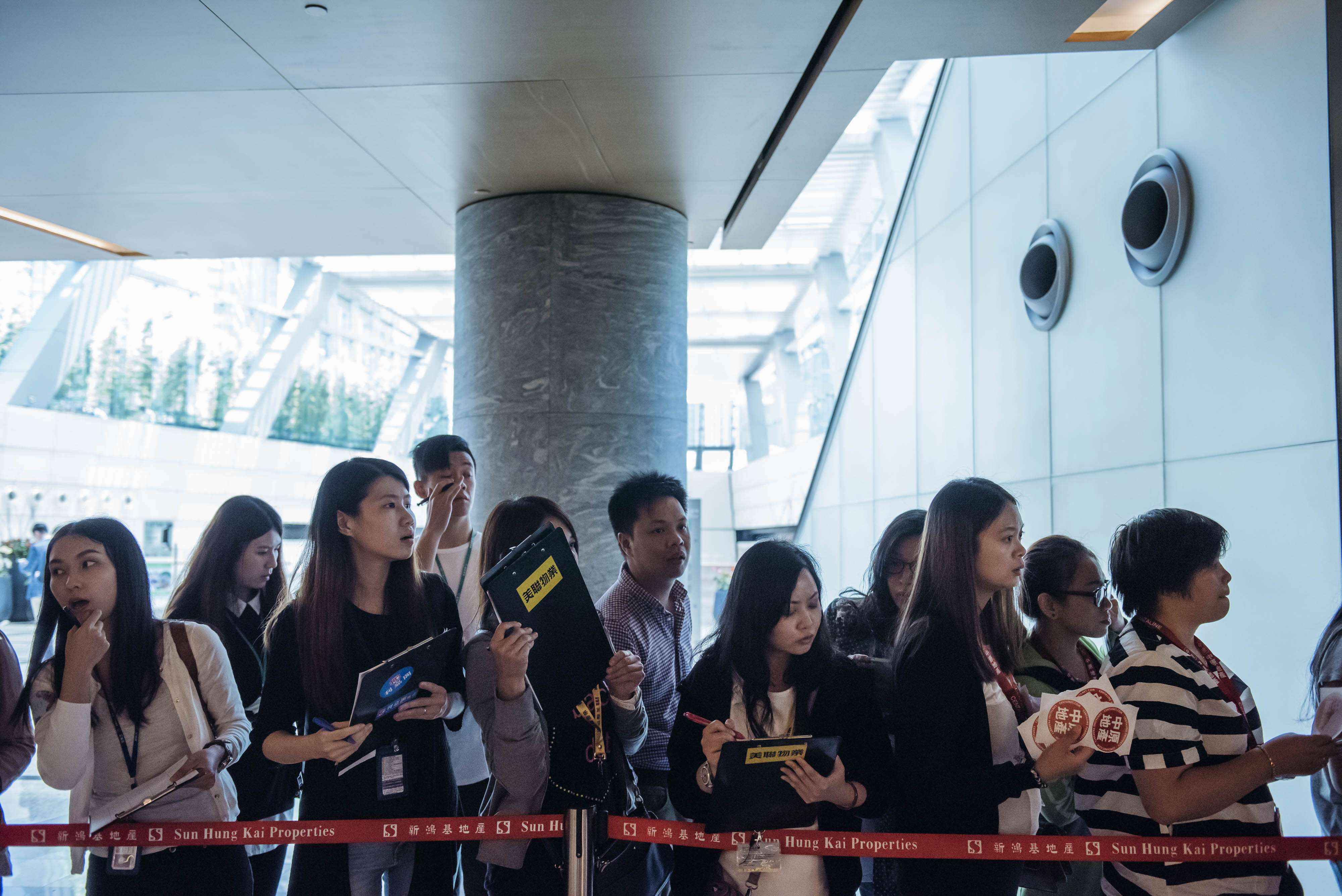 Real estate agents waiting last weekend for potential buyers outside the sales office of Park Yoho Venezia, a residential property developed by Sun Hung Kai Properties Ltd in Hong Kong. Anthony Kwan, Bloomberg