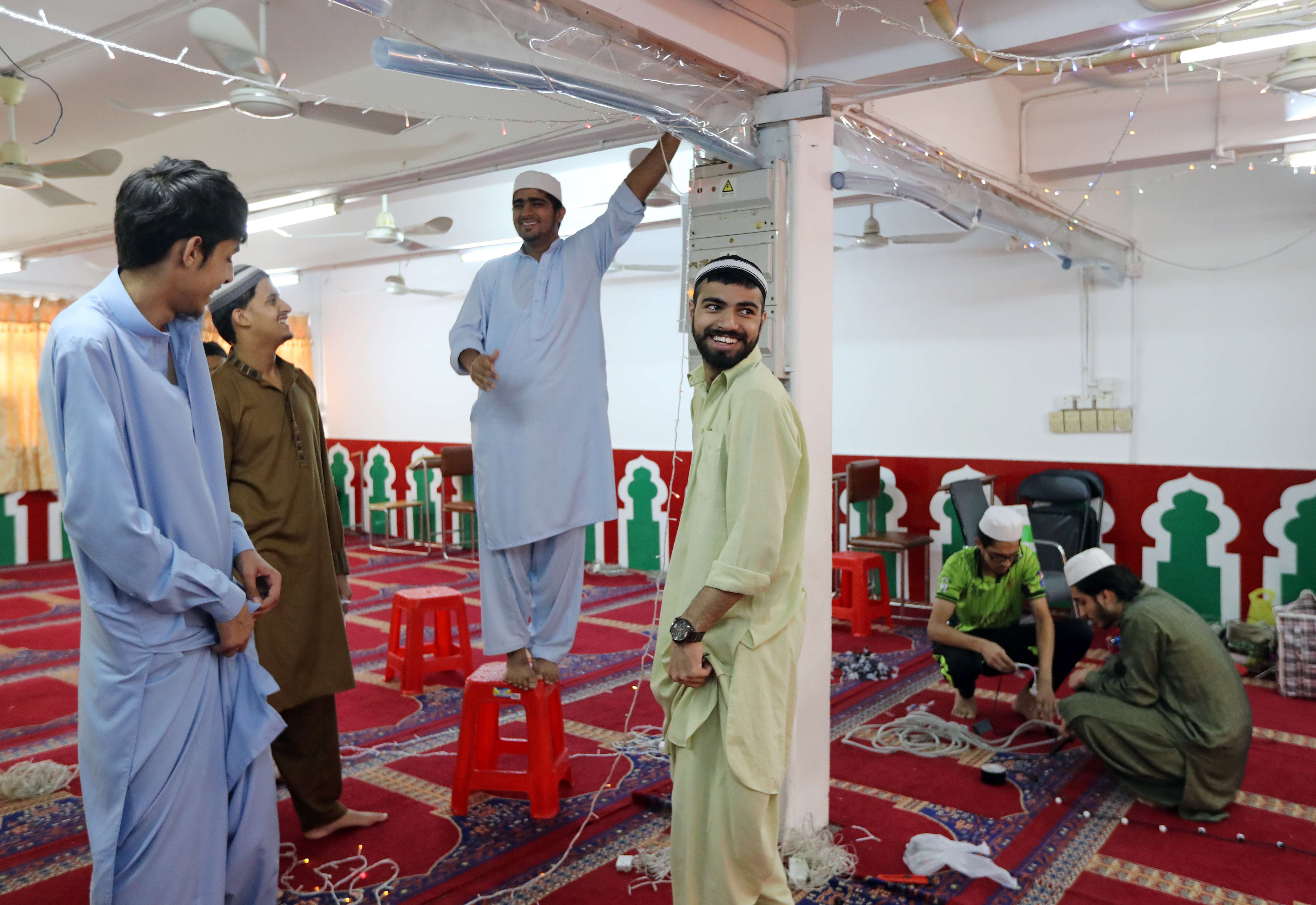 Muslims share a light moment as they decorate the Idara Minhaj-ul-Quran mosque in Kwai Chung in preparation for celebrations of the end of Ramadan. Photo: Bruce Yan
