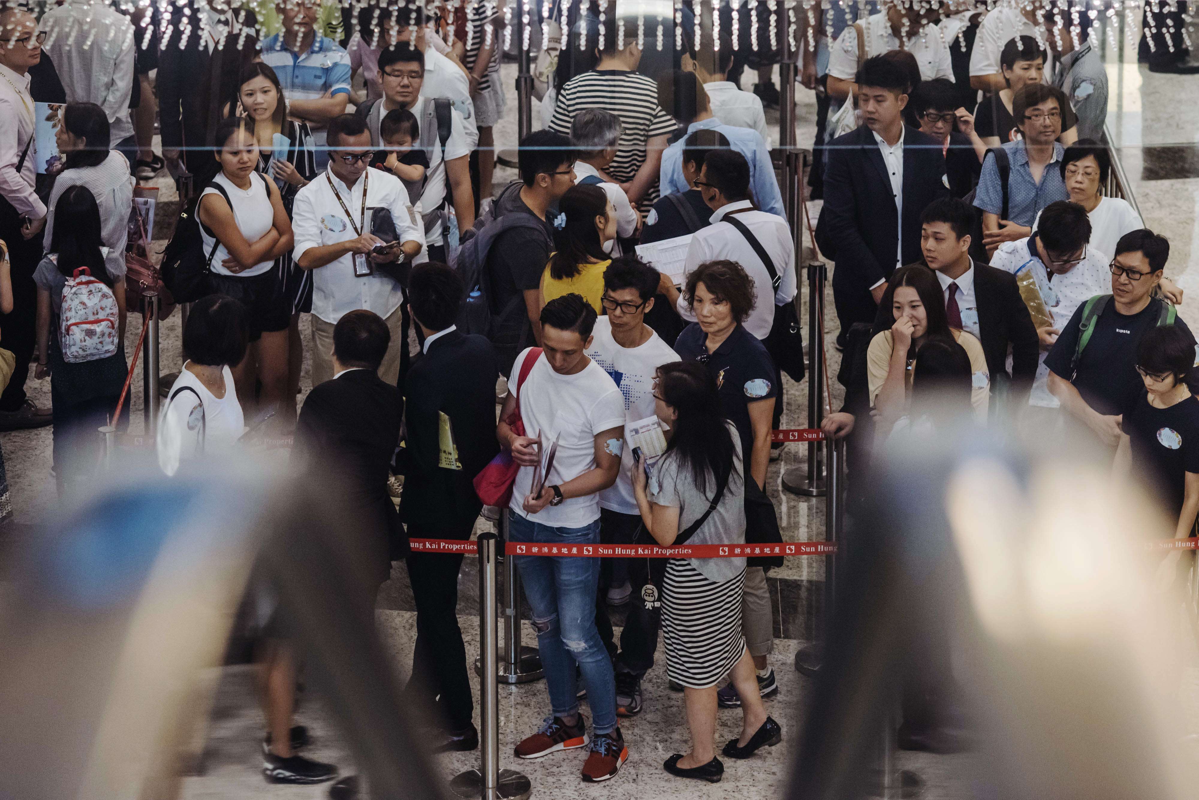Potential buyers and real estate agents stand in line last month, outside the sales office of Park Yoho Venezia, a residential property developed by Sun Hung Kai Properties. Photo: Anthony Kwan, Bloomberg