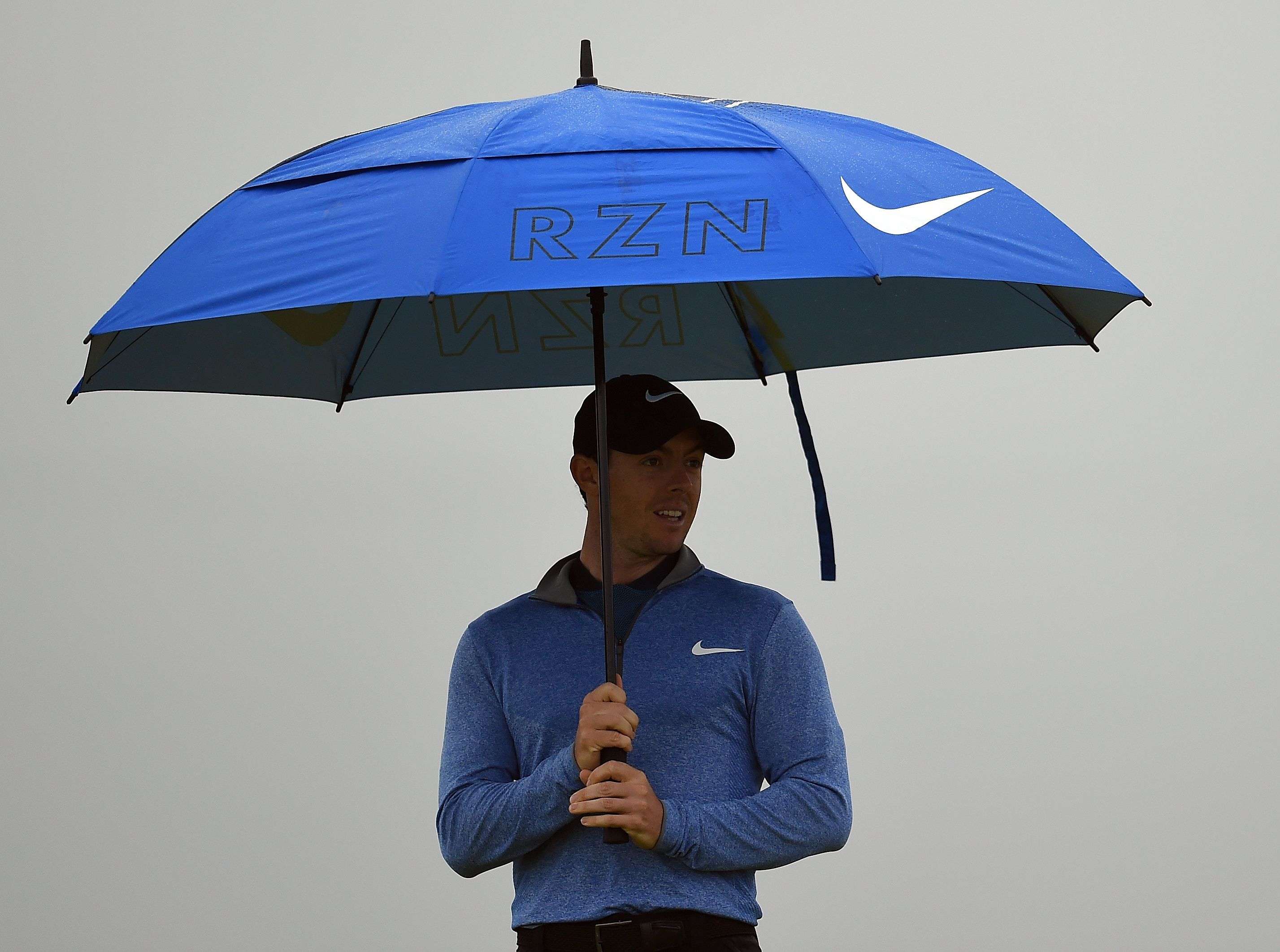 Northern Ireland's Rory McIlroy shelters from the rain AFP