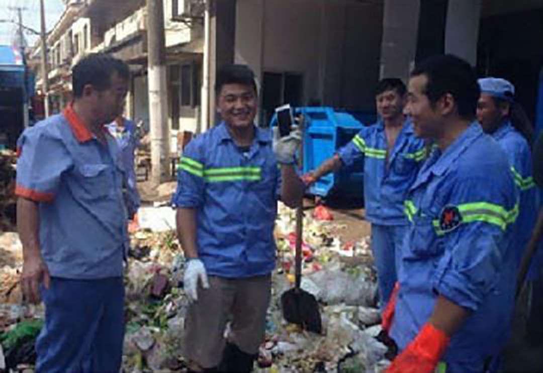 A sanitation worker proudly holds the missing phone. Photo: Thepaper.cn