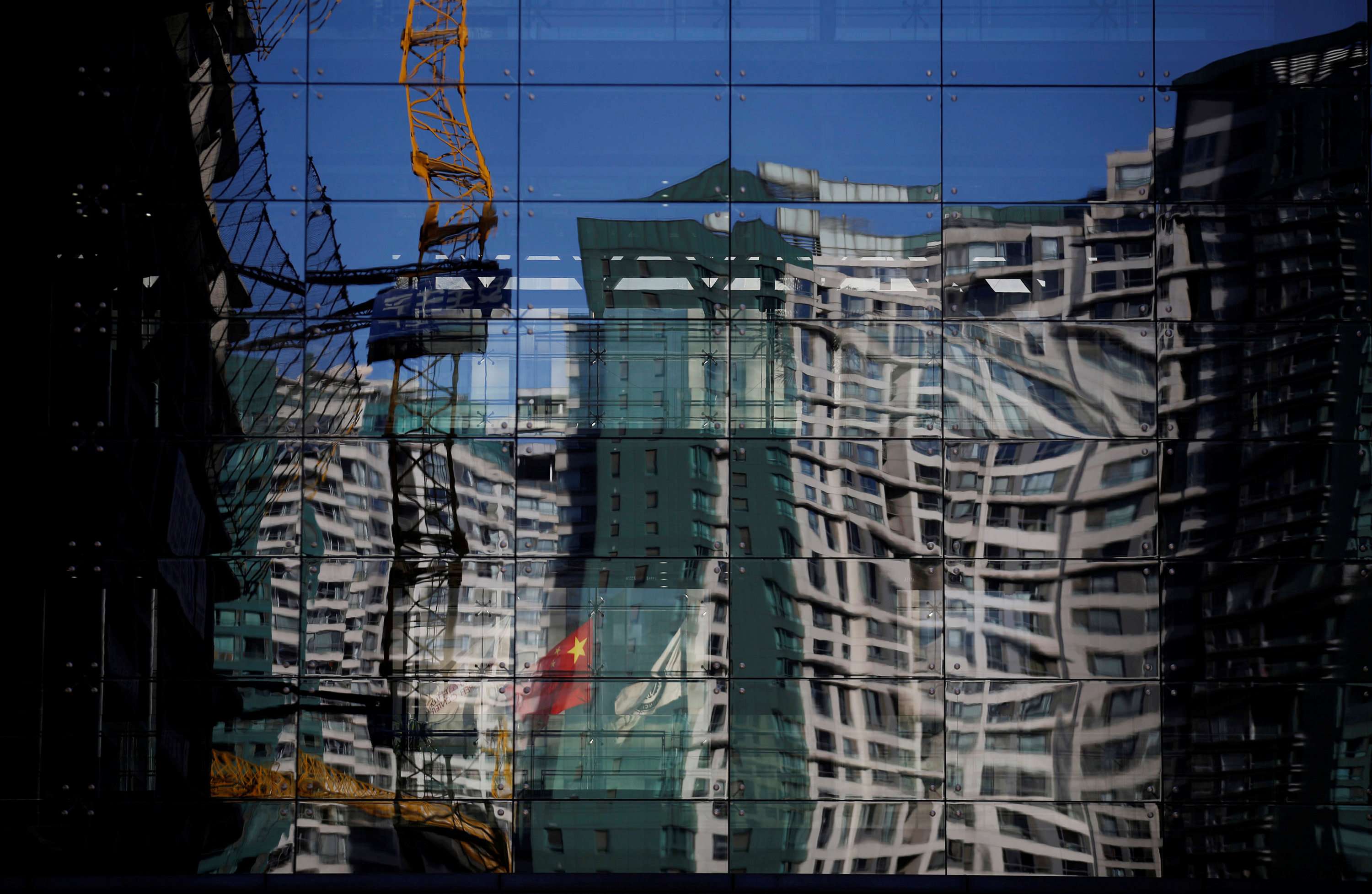 A construction site and a residential building are reflected in the glass wall of a building in Beijing. To fully understand China, one must first understand the rest of the world. Photo: Reuters