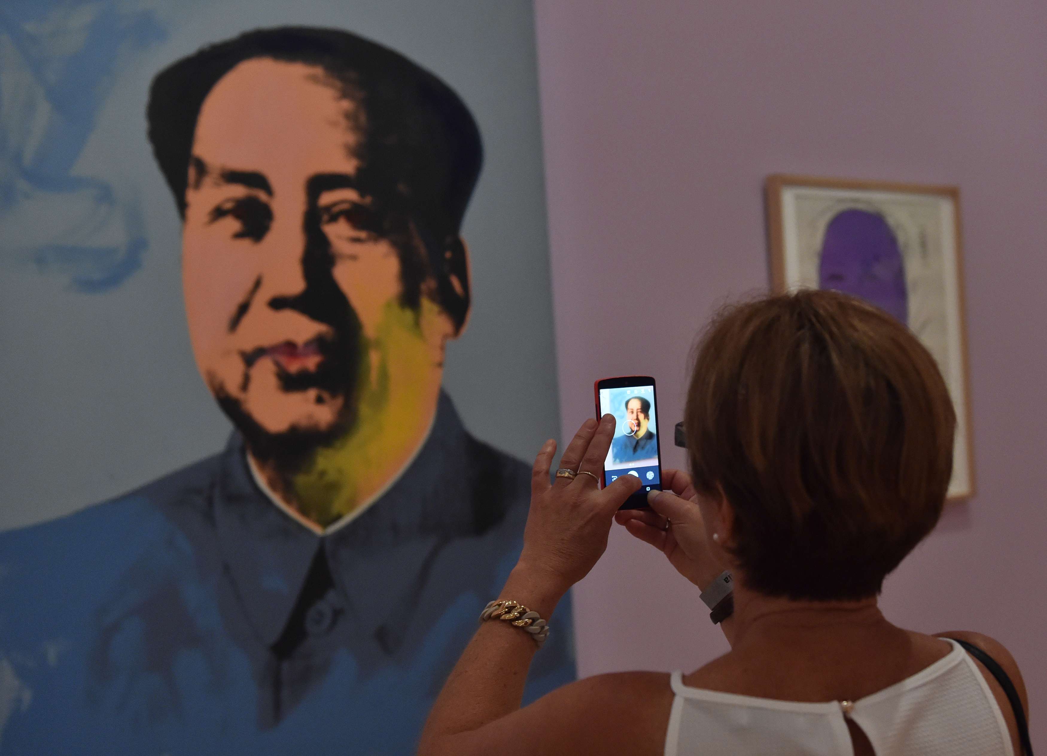 A woman in Melbourne takes a picture of a portrait of Mao Zedong by Chinese dissident artist Ai Weiwei. Photo: AFP