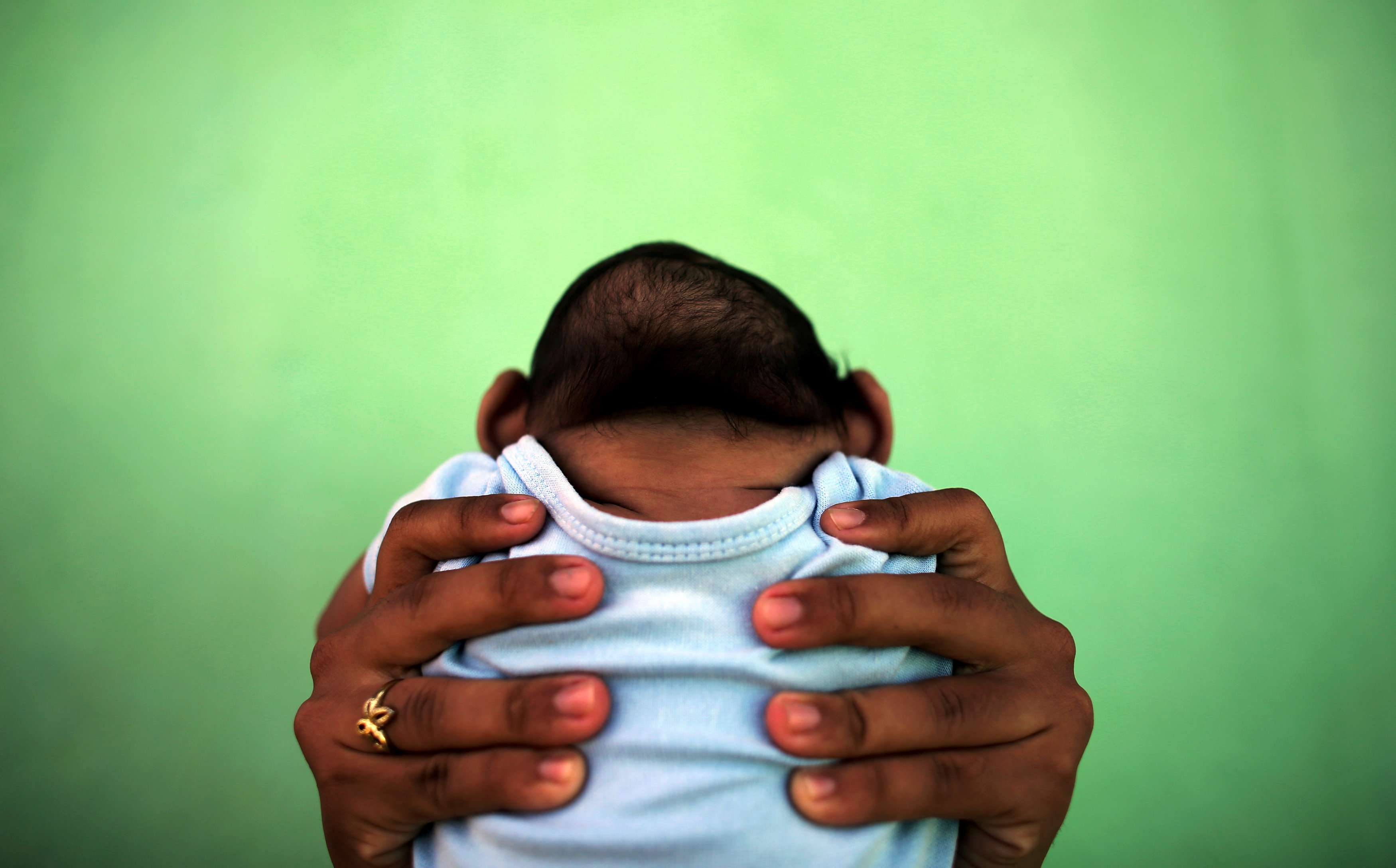 A four-month-old baby born with microcephaly is held by his mother in front of their house in Olinda, near Recife, Brazil. Pregnant women infected by the mosquito-borne Zika virus run the risk of giving birth to babies with this defect. Photo: Reuters