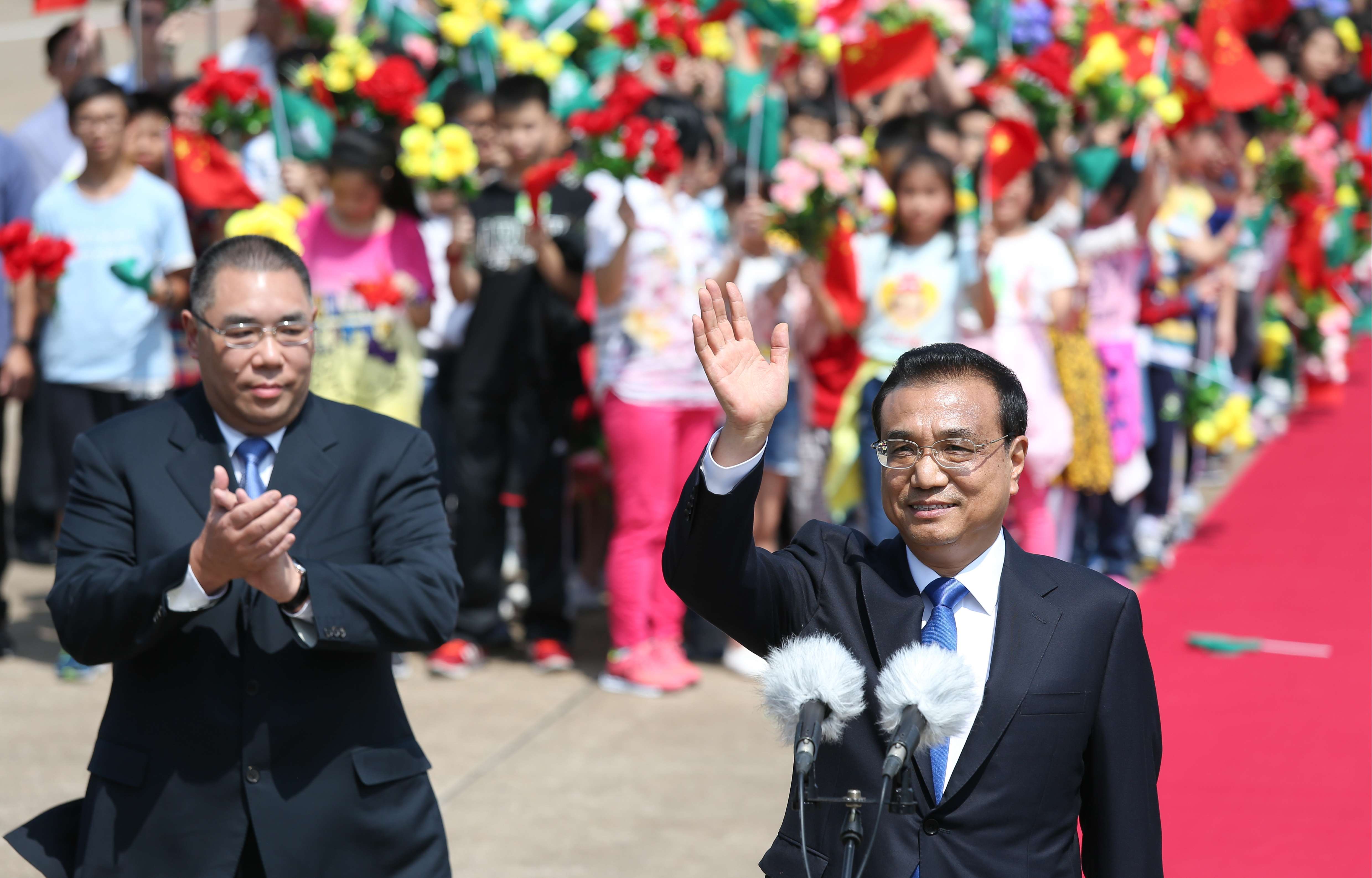 Premier Li Keqiang greets the colourful crowds gathered to welcome him at Macau International Airport on October 10, as Macau Chief Executive Fernando Chui applauds. Photo: Dickson Lee