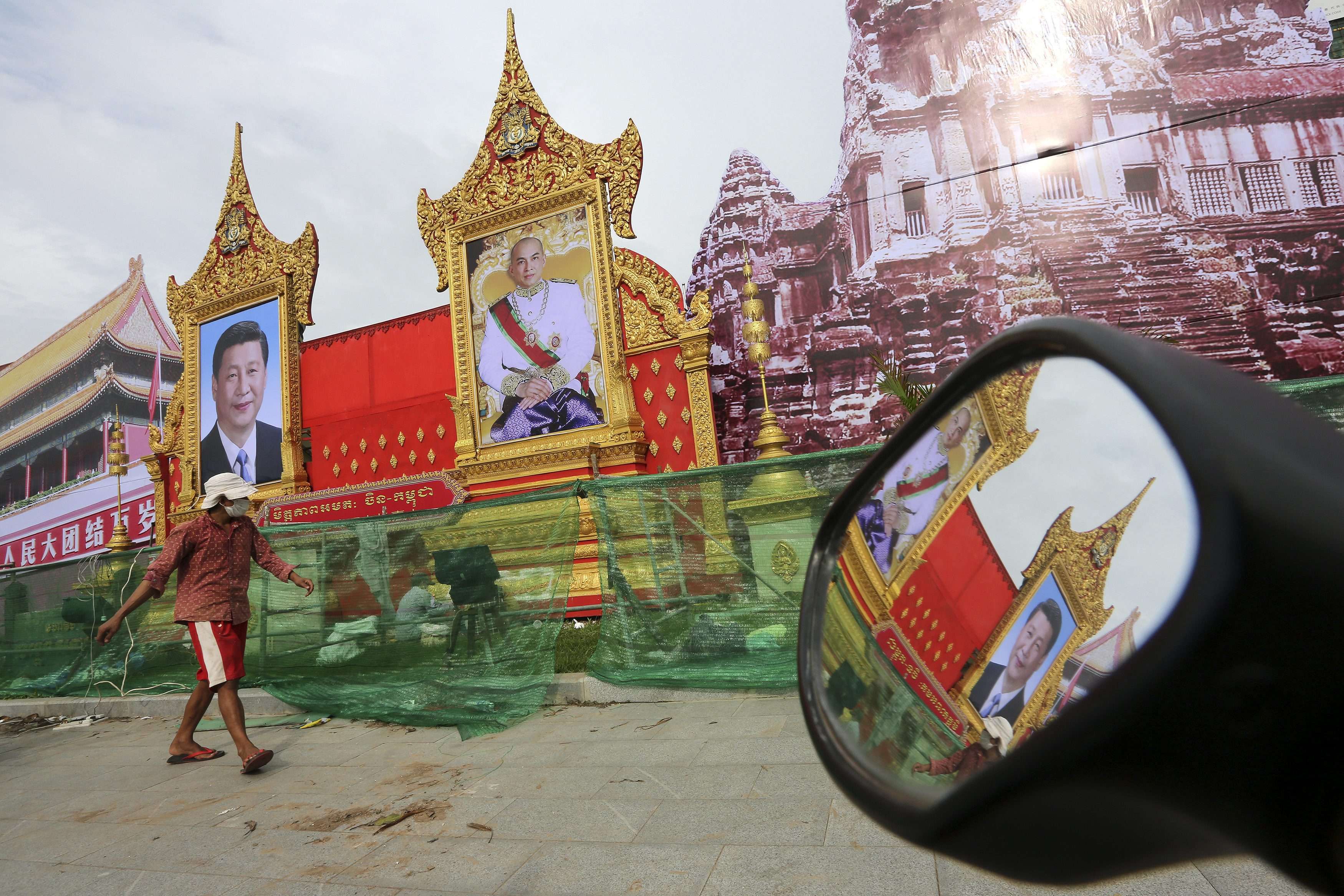 A Cambodian passes portraits of Chinese President Xi Jinping and Cambodian King Norodom Sihamoni in Phnom Penh, Cambodia ahead of Xi’s visit. Photo: EPA