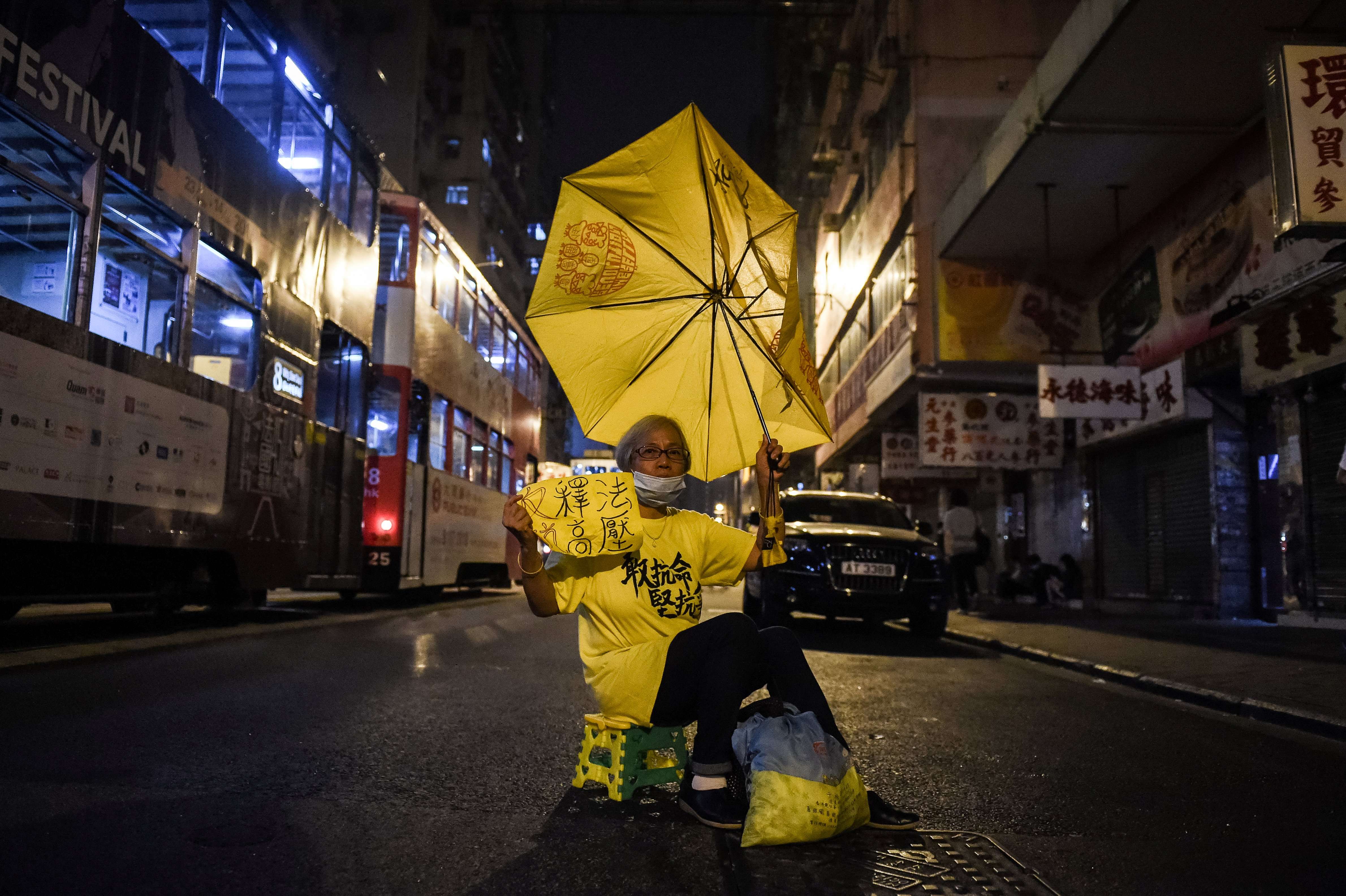 A protestor holds up a yellow umbrella in a street in Hong Kong on November 7, 2016. Hong Kong police used pepper spray November 6 to drive back hundreds of protesters angry at China's decision to intervene in a row over whether two pro-independence lawmakers should be barred from the city's legislature. Photo: AFP