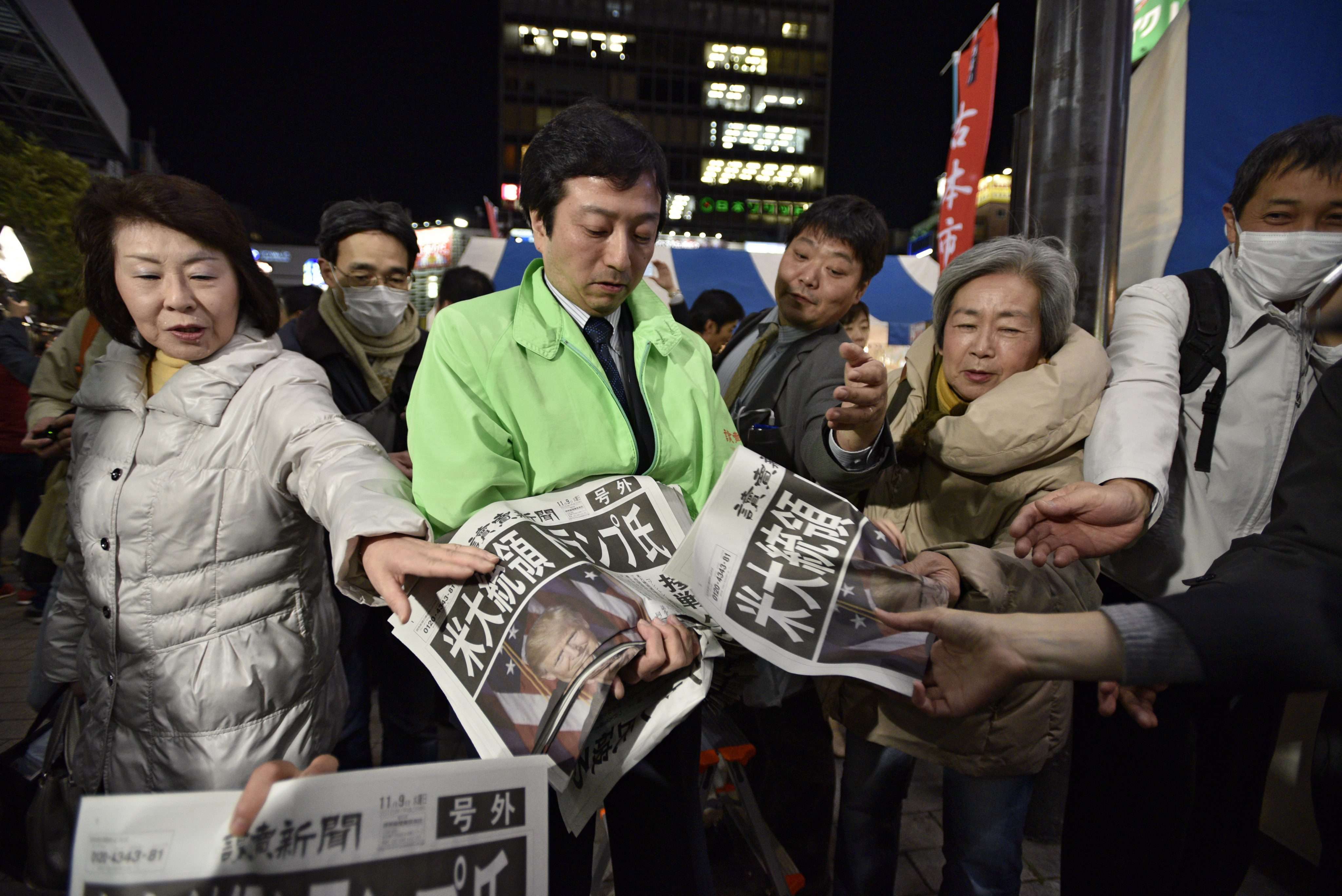 Passers-by in Tokyo reach for extra editions of newspapers reporting Donald Trump’s victory in the US presidential election on November 9. Photo: EPA