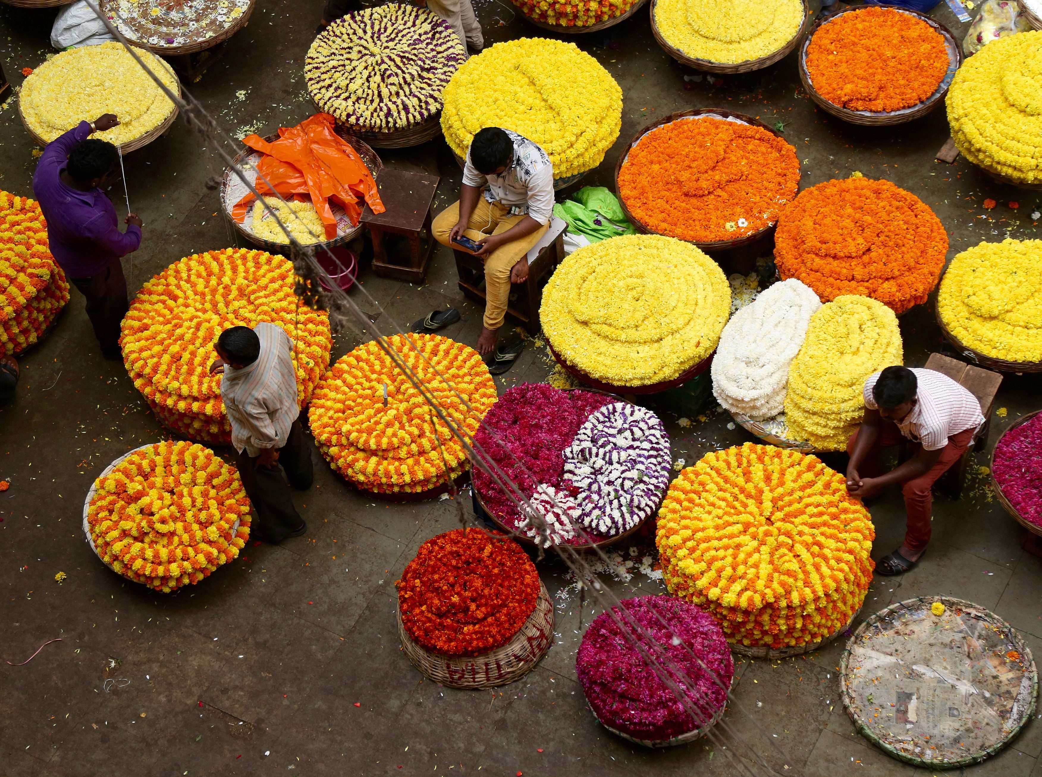 Indian flower vendors wait for customers at a market in Bangalore. Indian businesses have been hit hard by the lack of currency notes in the wake of the government’s decision to ban high denomination notes. Photo: EPA