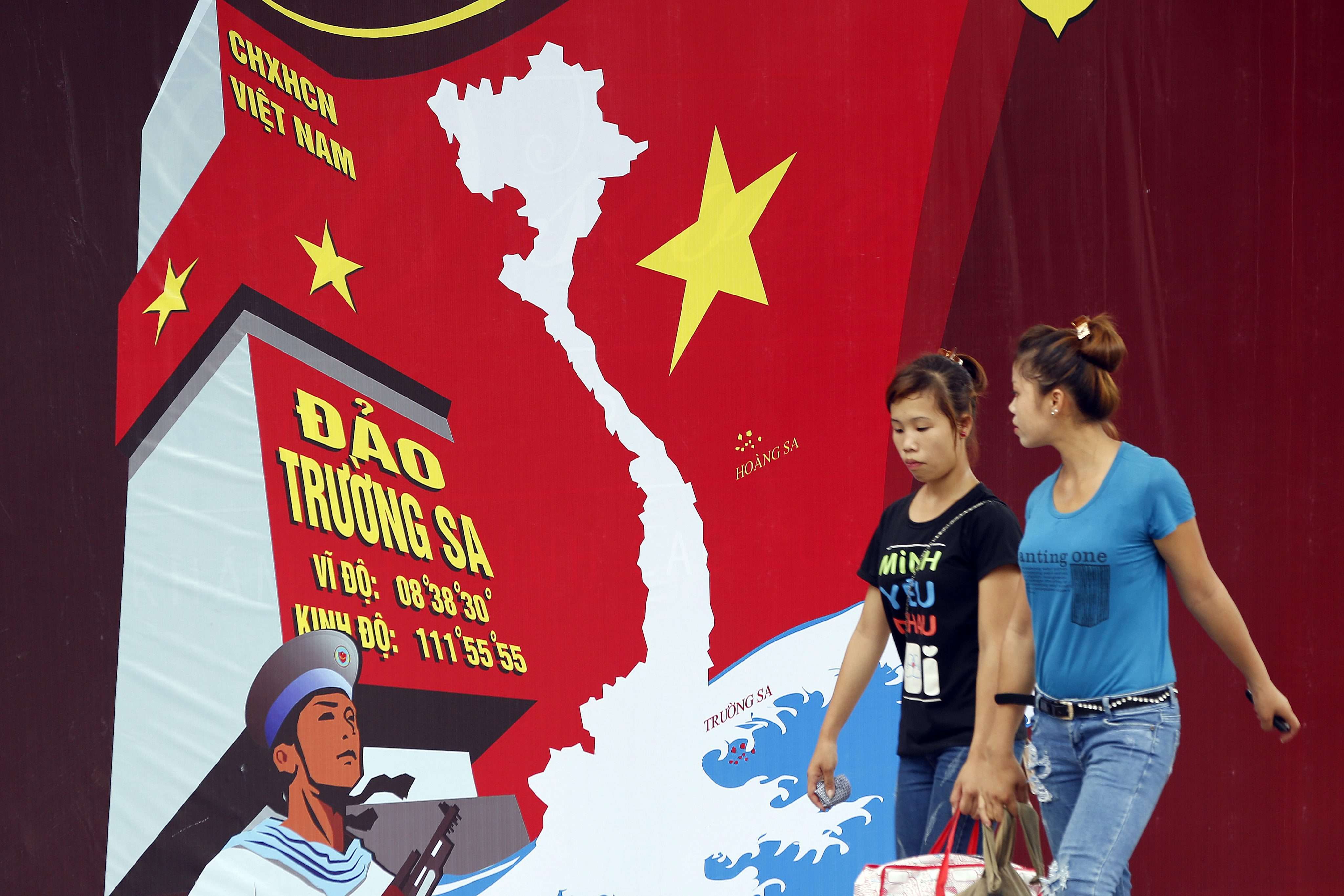 Two women pass a board featuring a map of Vietnam and the words 'Spratly Islands' in a street in Hanoi, Vietnam. Diplomatic disputes between China and Vietnam have prompted resentment of Chinese tourists in the country. Photo: EPA