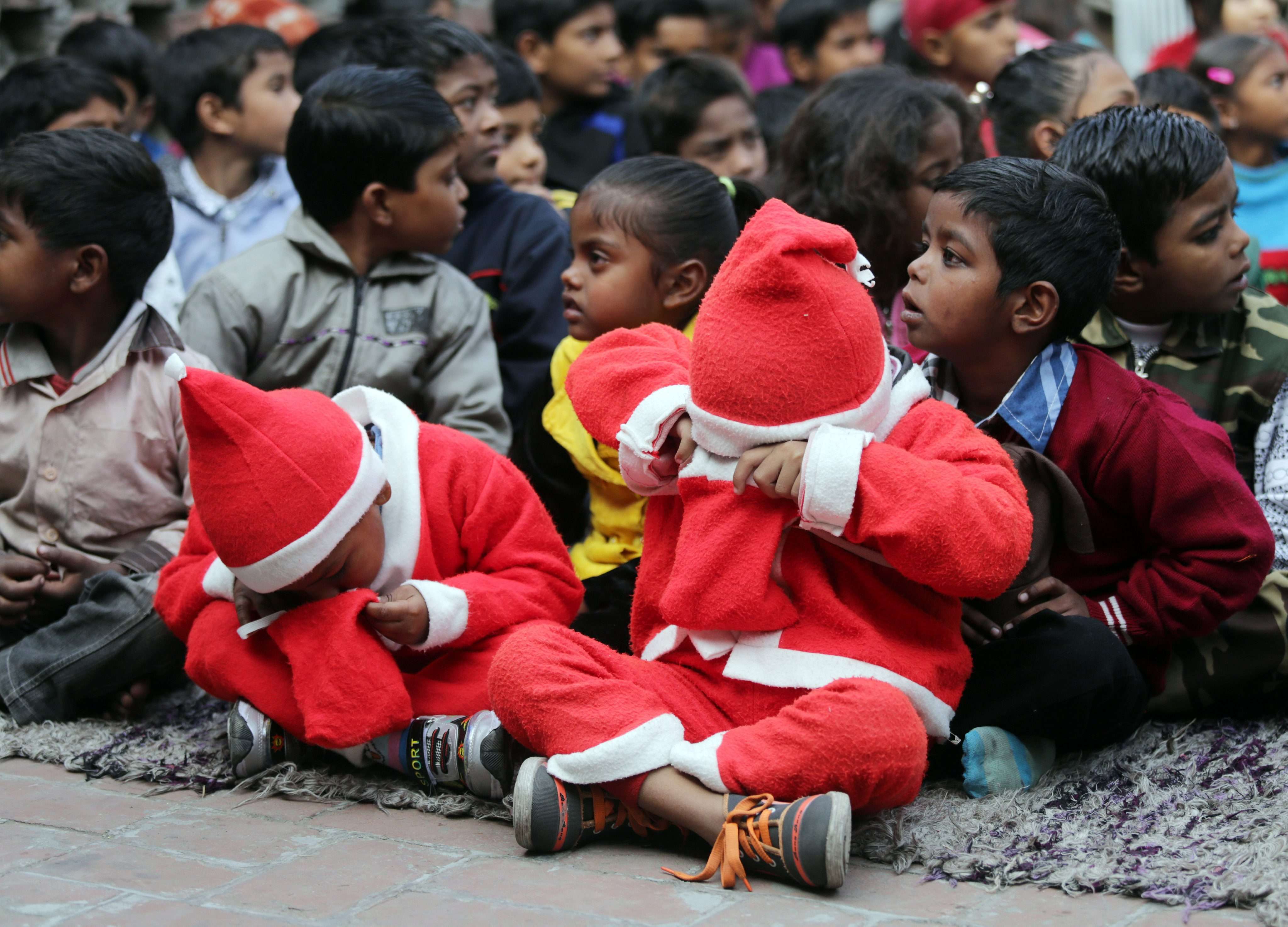 Children dressed as Santa Claus peer into their goodie bags as they take part in Christmas celebrations with underprivileged children, organised by an education-focused NGO in Amritsar, India, on Christmas Day. Many of the slum children studying under the guidance of the NGO work as day labourers or rag pickers. Photo: EPA