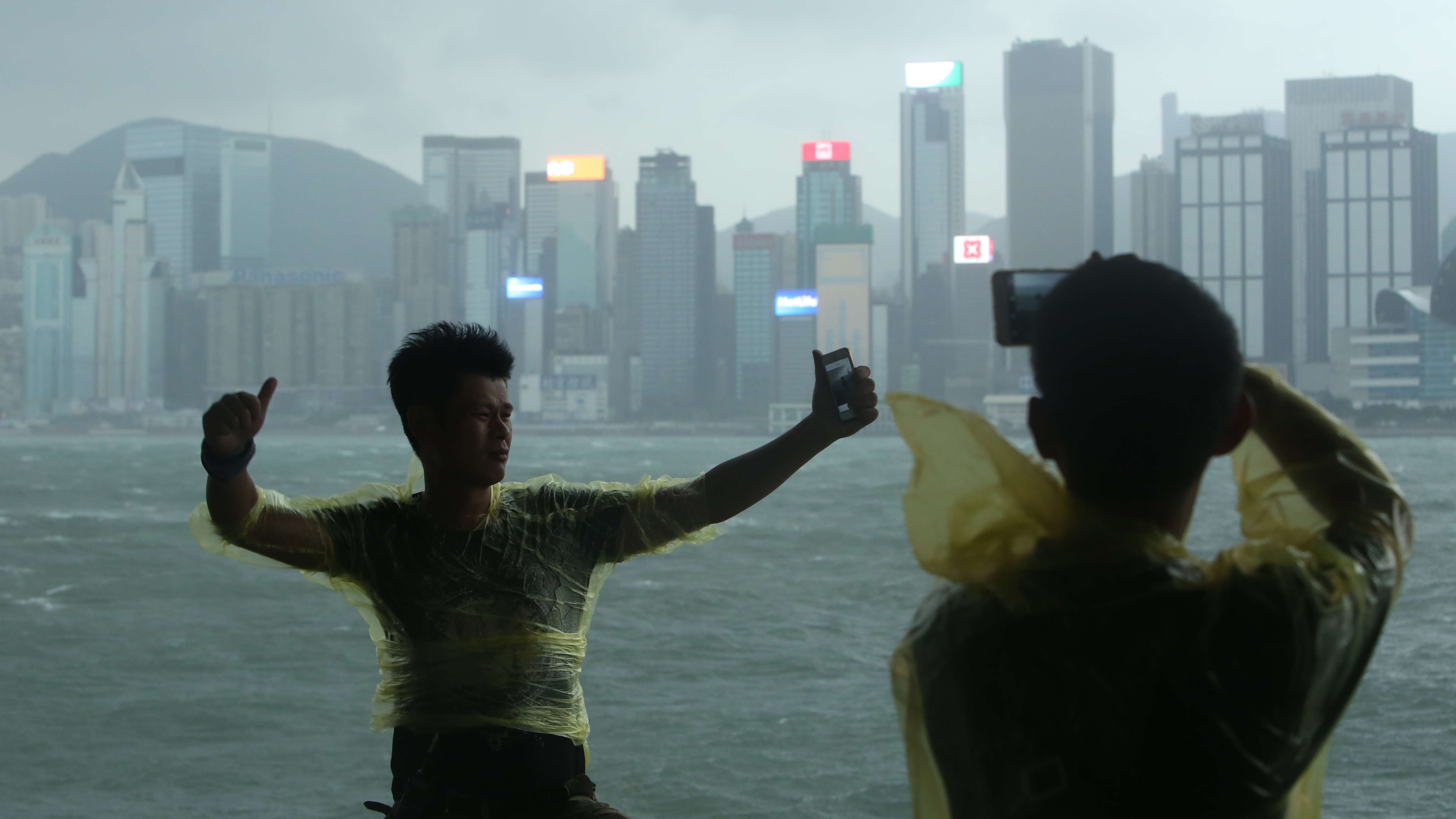 A Hongkonger strikes a Bruce Lee-like pose near the kung fu star’s statue on the Tsim Sha Tsui waterfront as typhoon Haima hit the city. Photo: Edmond So