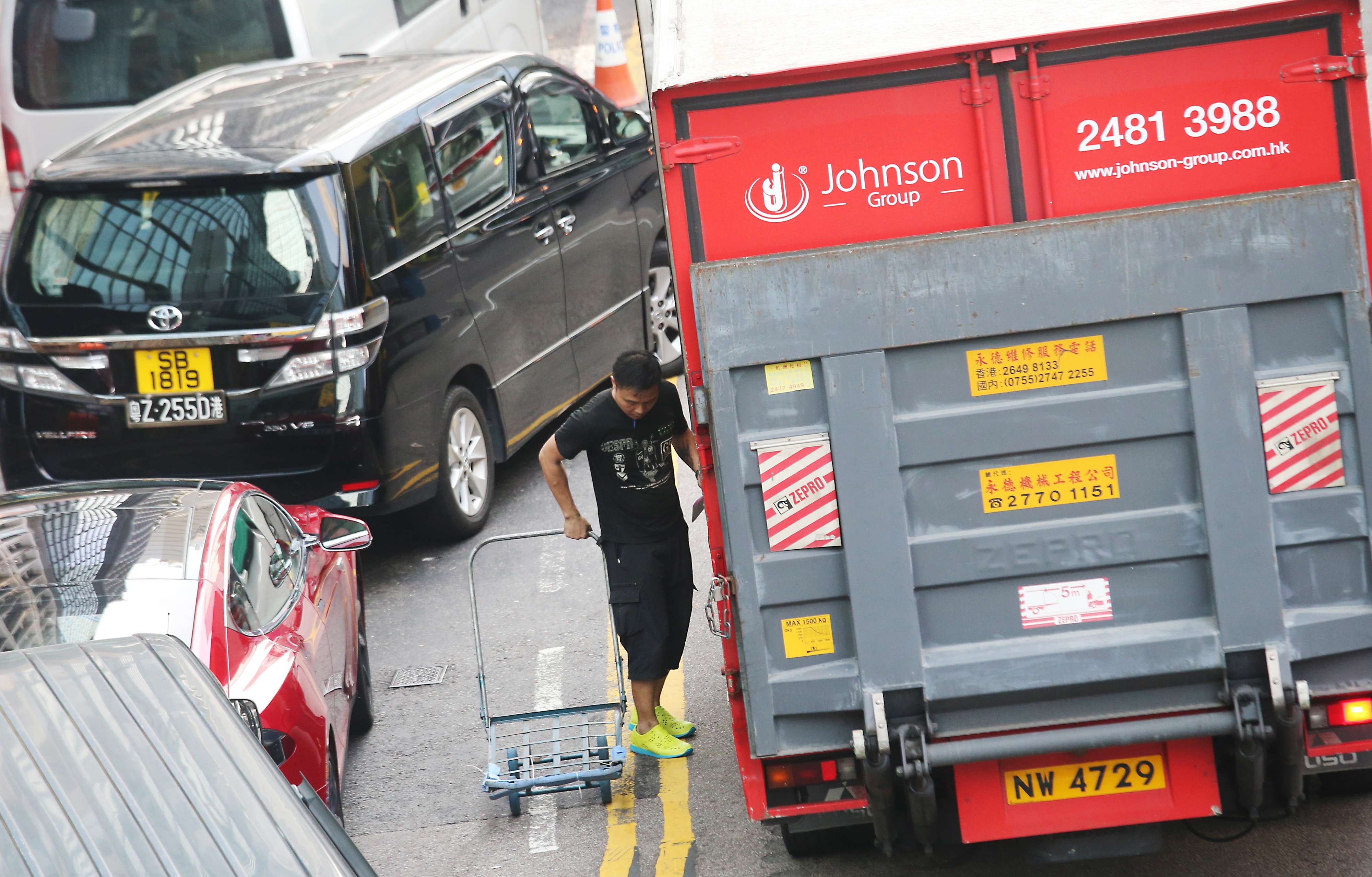 Illegally parked cars mean delivery vehicles have to occupy traffic lanes. Photo: David Wong