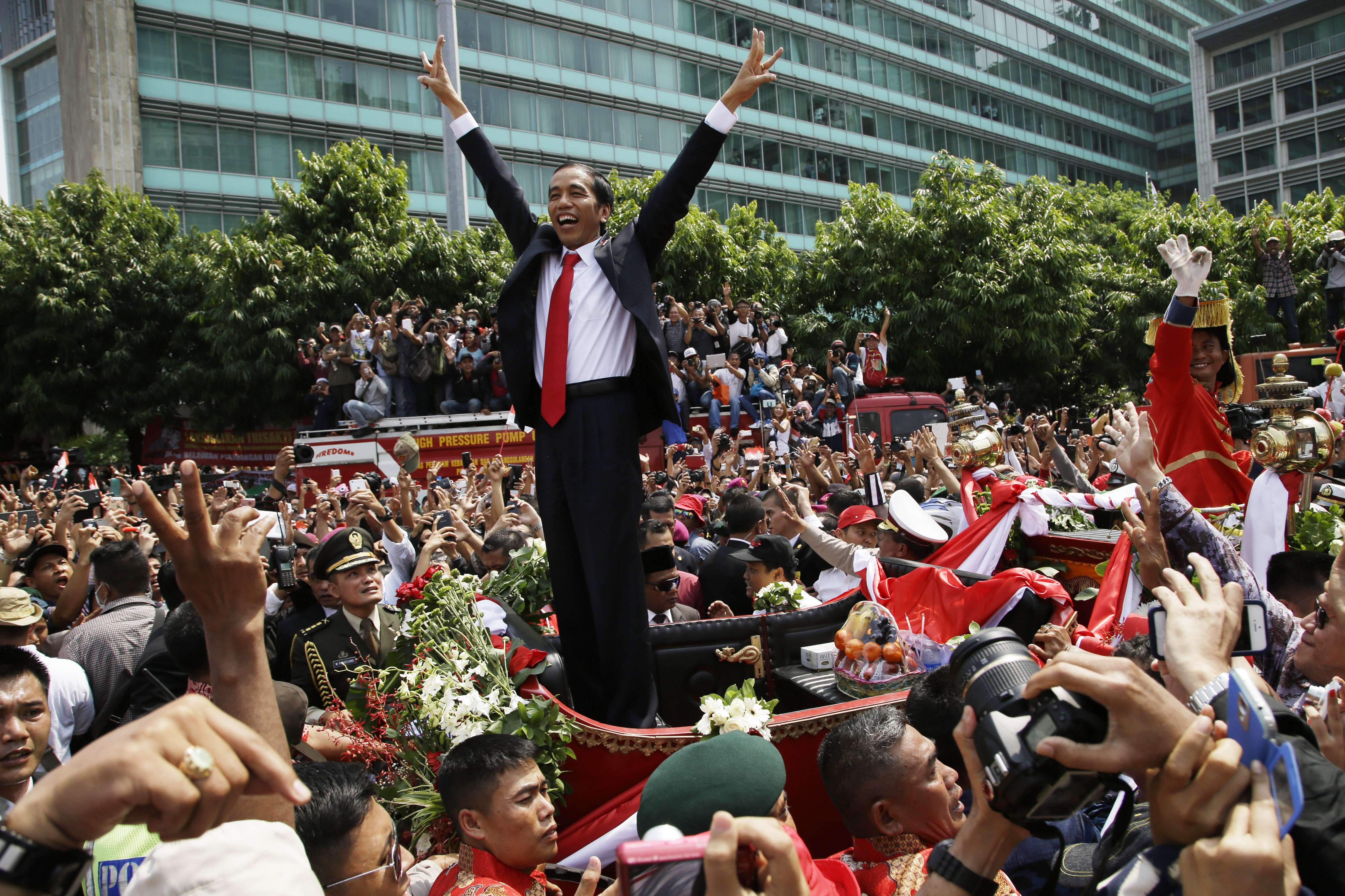 A jubilant President Joko Widodo gestures to the crowd during a street parade following his inauguration in Jakarta on October 20, 2014. After great success with his landmark tax amnesty plan and coalition-building, Widodo may be risking it all by siding with Islamic conservatives. Photo: AP