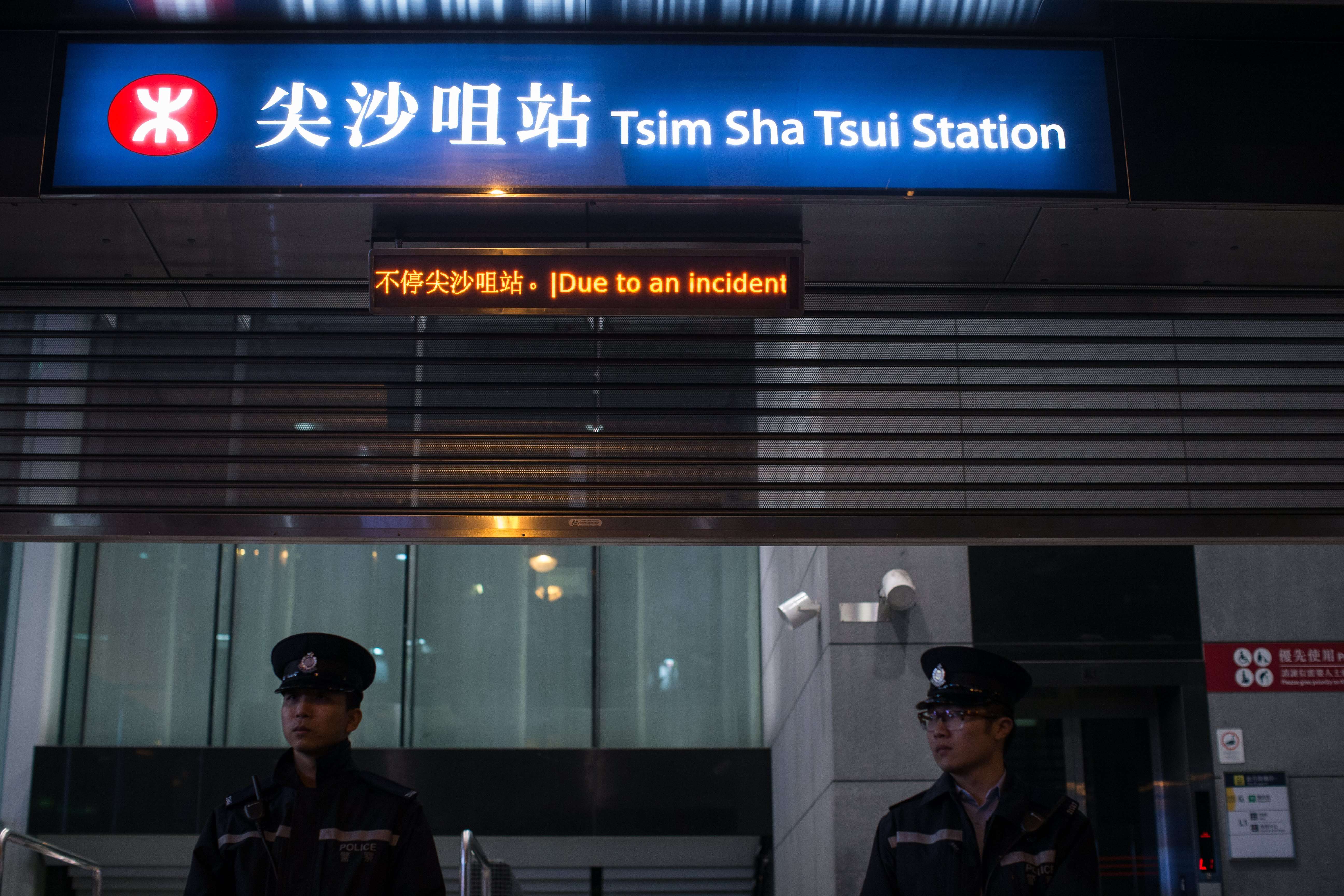 Police officers stand guard outside a closed Tsim Sha Tsui MTR station on February 10, after a man hurled a firebomb on a crowded train during the evening rush hour, injuring at least 18 people. Photo: EPA