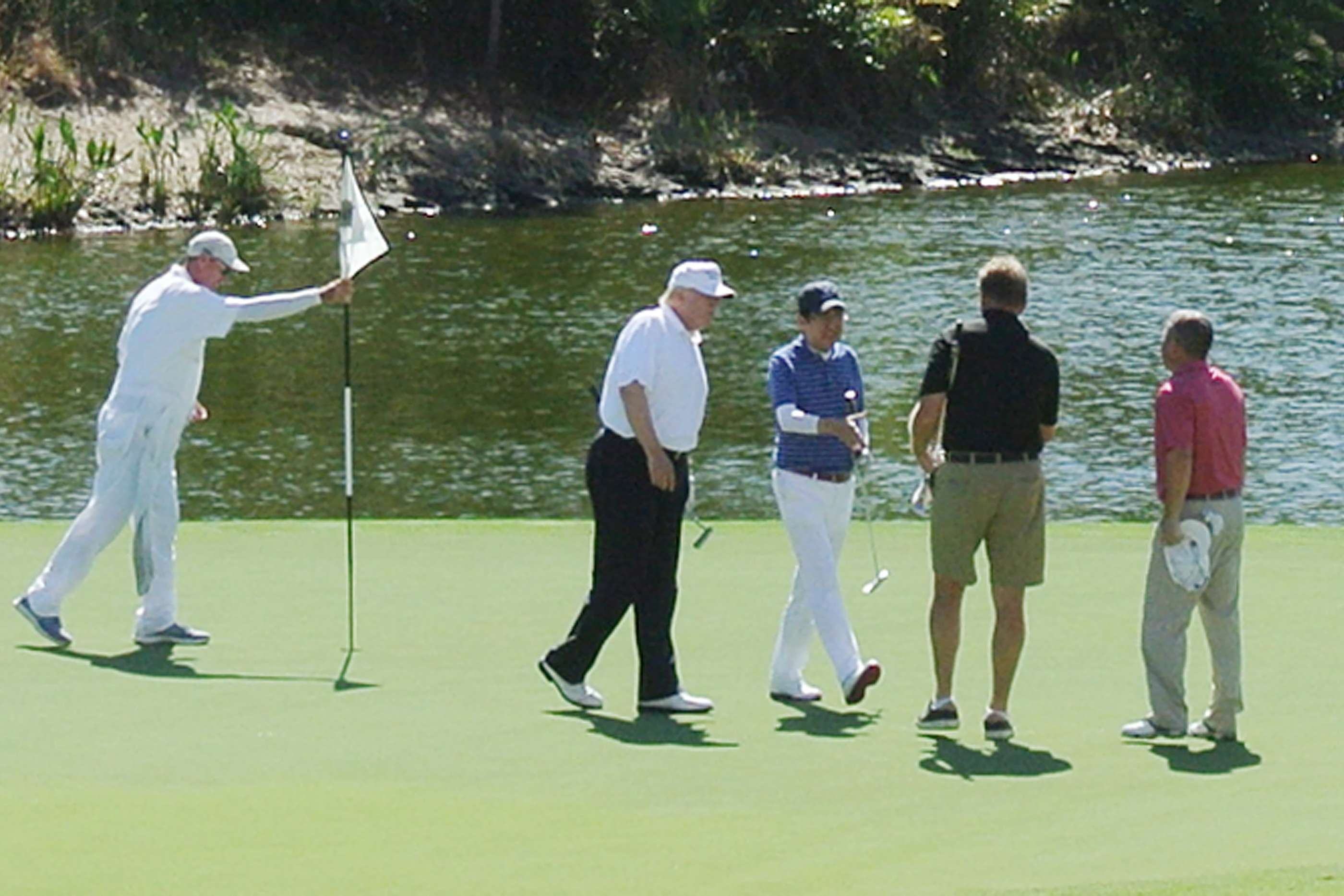 US President Donald Trump, second from left, and Japan's Prime Minister Shinzo Abe, centre, play a round of golf in Florida. Photo: AFP