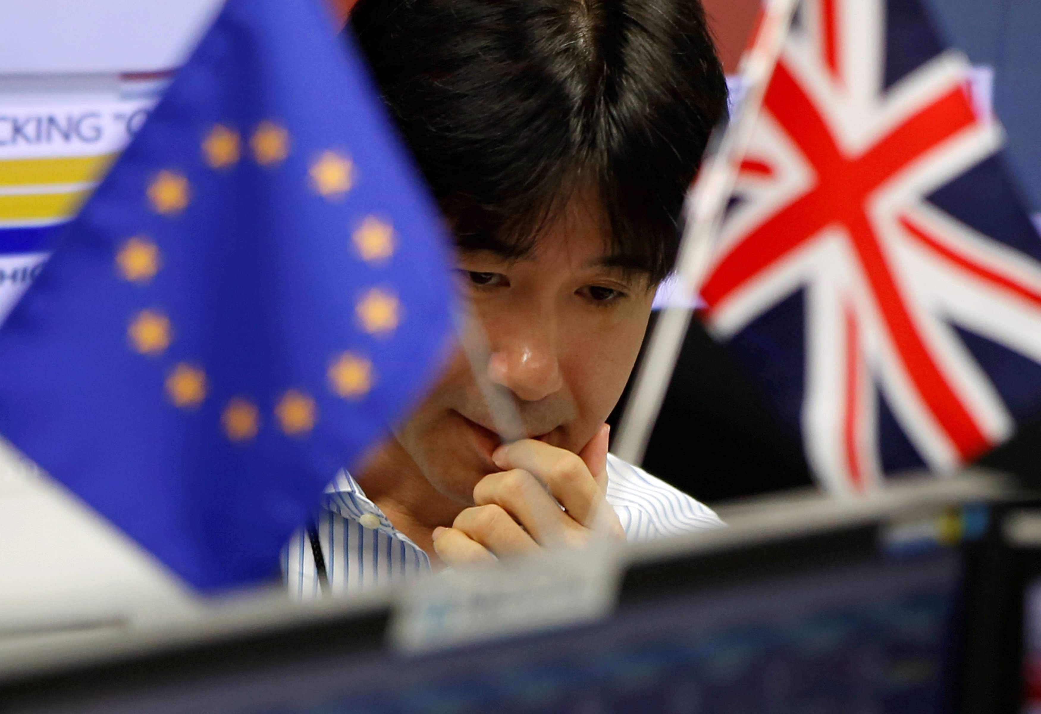 A foreign exchange worker in Tokyo, pictured between the European and British flags. Photo: Reuters