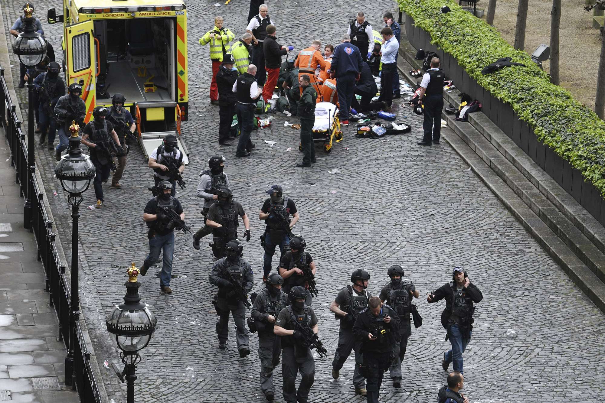 Armed police walk past emergency services attending to injured people outside the Houses of Parliament in London on Wednesday. Photo: AP