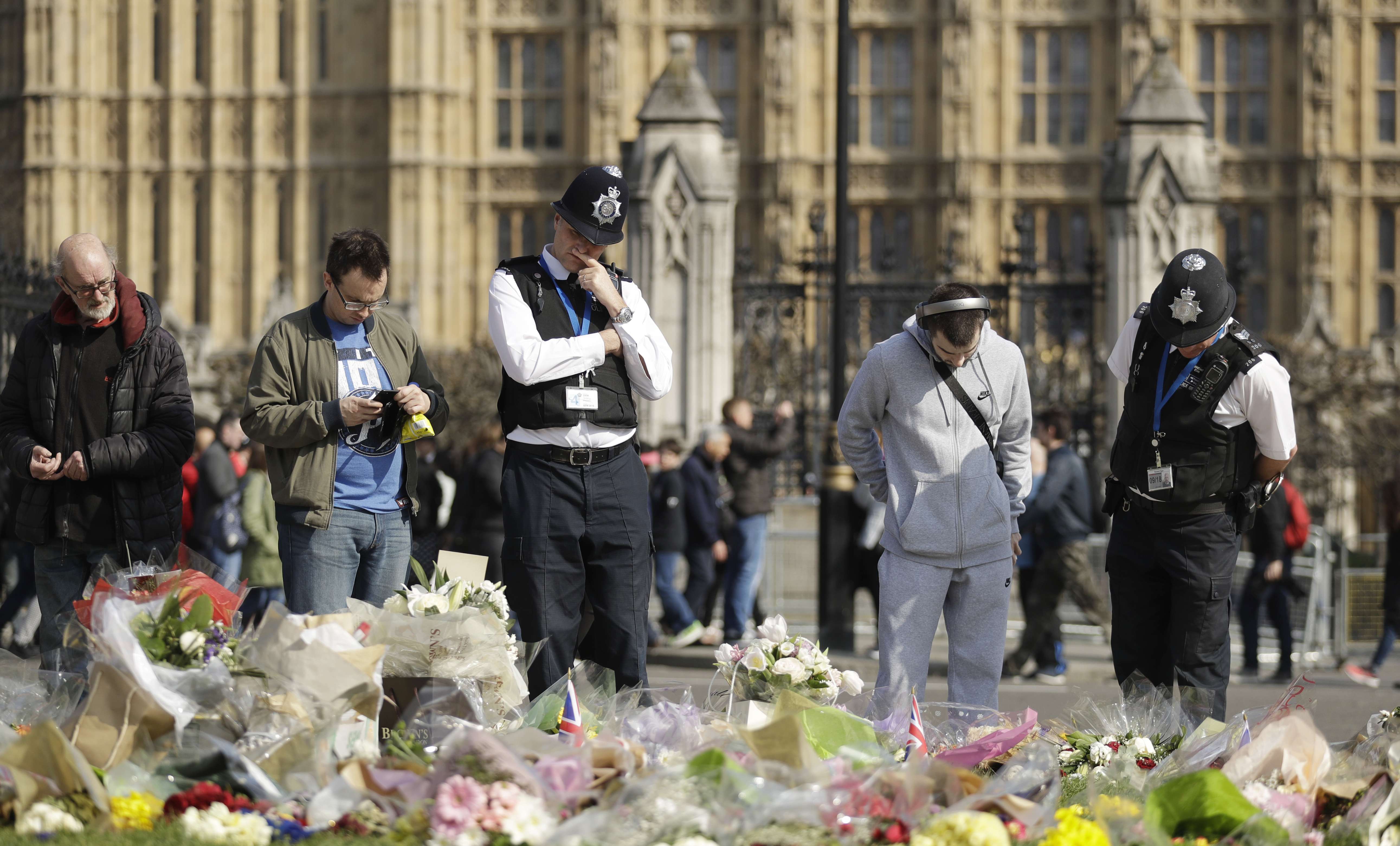 Police officers and members of the public look at the floral tributes to the victims of the Westminster attack placed outside the Palace of Westminster, London, on Monday. Photo: AP