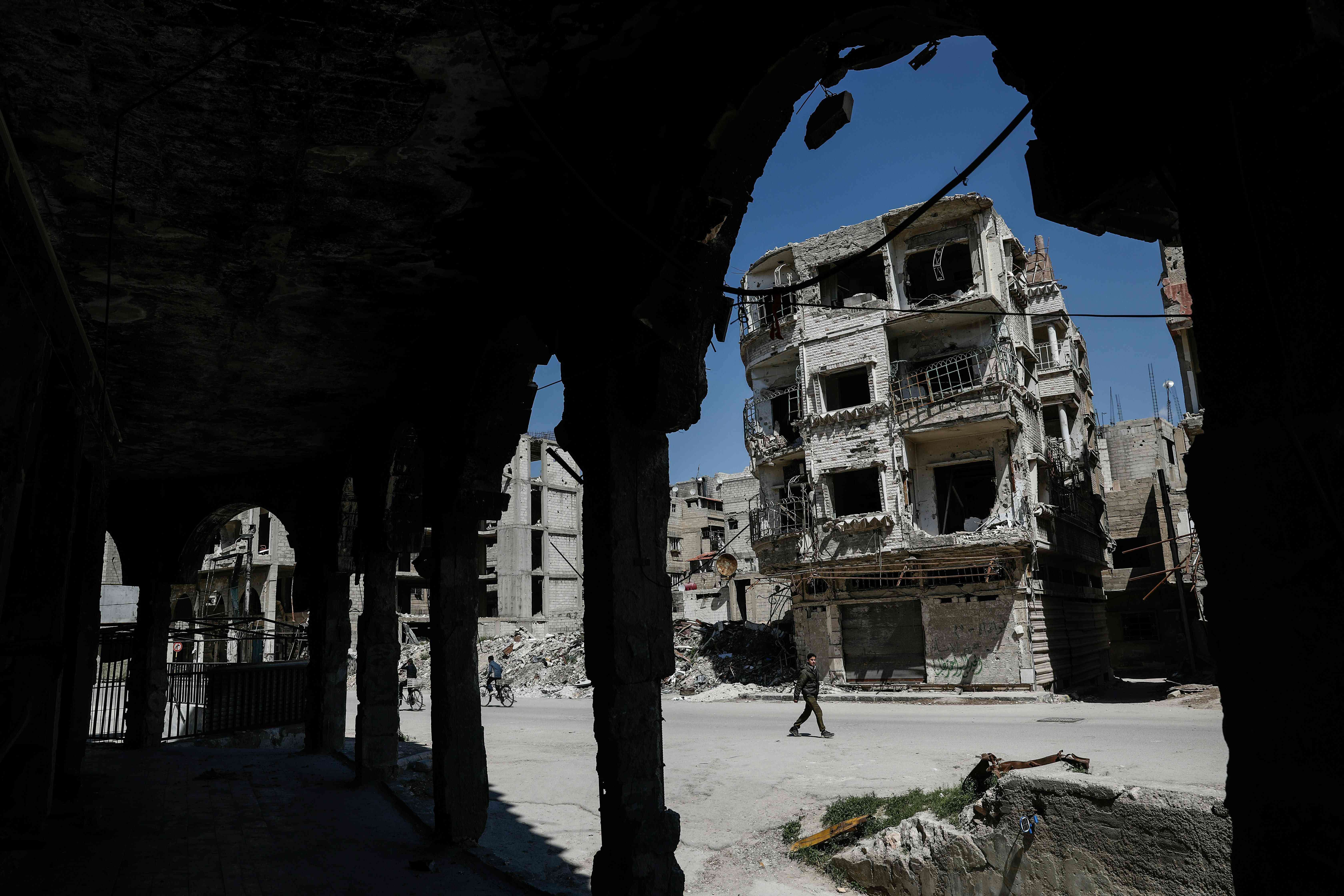 Syrians walk past damaged buildings on April 7 in the rebel-held town of Douma, on the eastern outskirts of Damascus. Photo: AFP