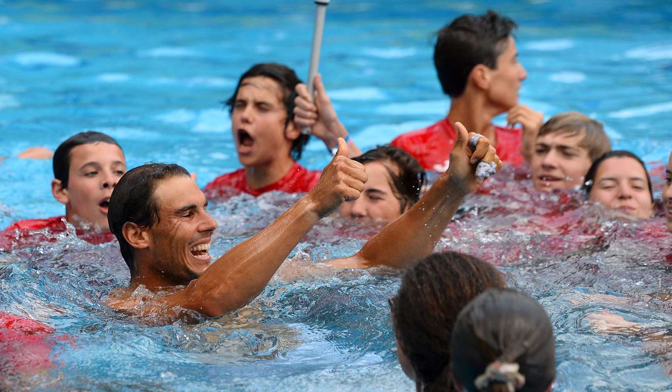 Rafael Nadal takes a dip in a swimming pool near the court with ballboys after defeating Dominic Thiem in the final. Photo: AFP