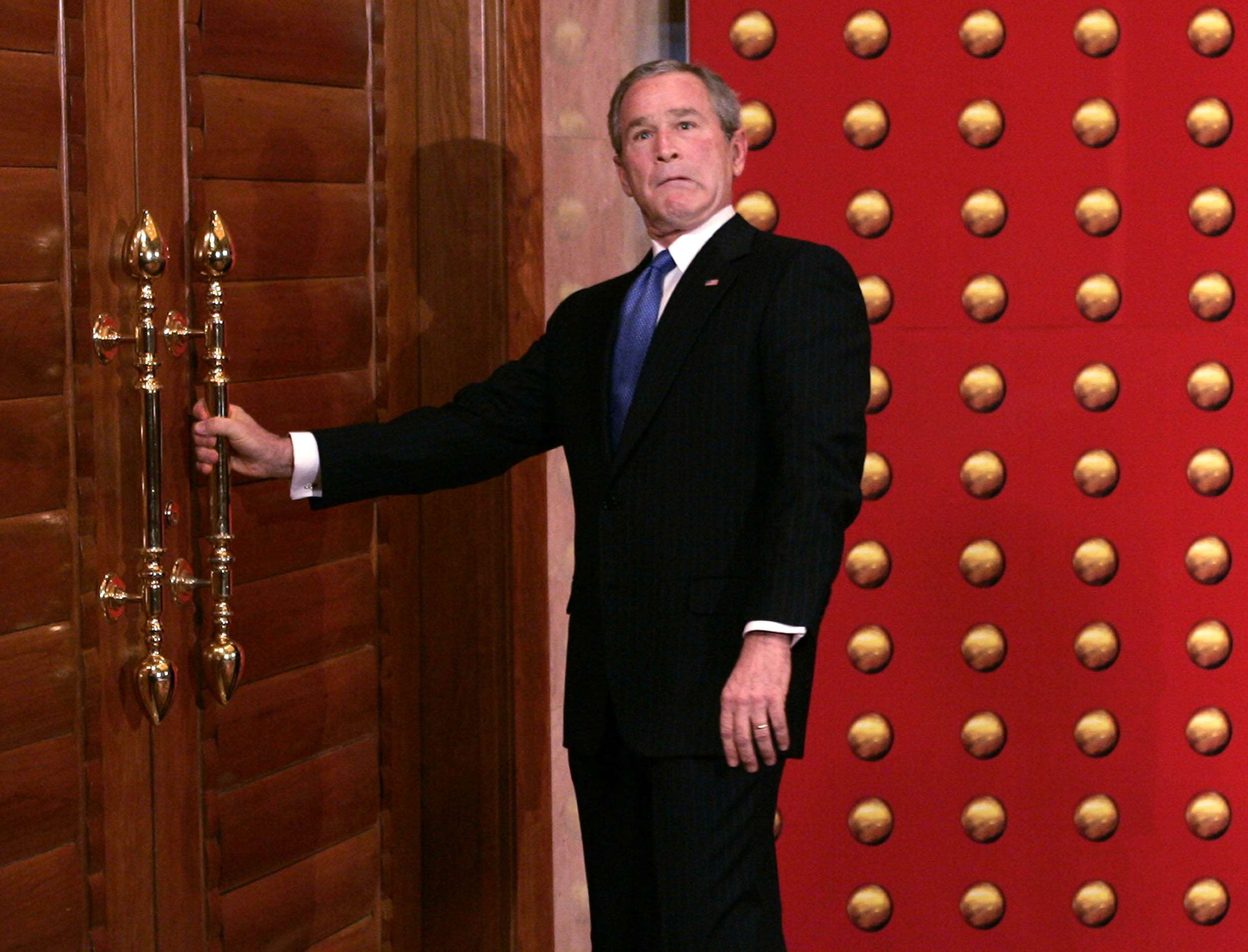 George W. Bush jokingly makes a face as he tries to open a locked door as he leaves a press conference in Beijing in 2005. File photo: AP