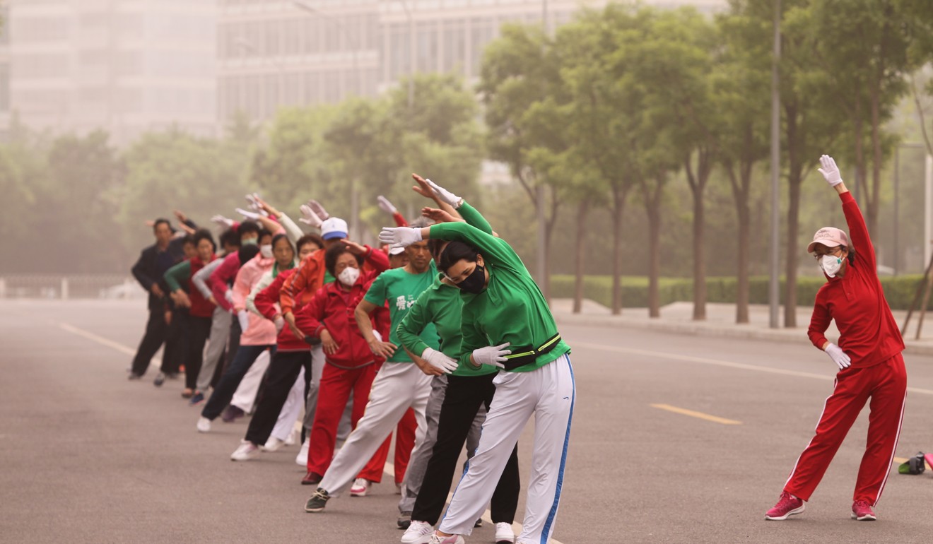 Seniors dance amid the sandstorm in Beijing on Thursday. Photo: Simon Song