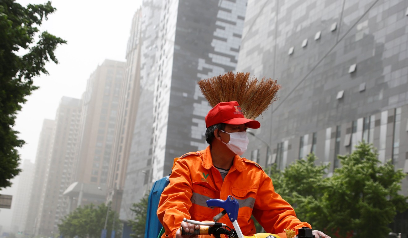 A street cleaner wears a face mask as a sand storm hits Beijing on Thursday. Photo: Reuters