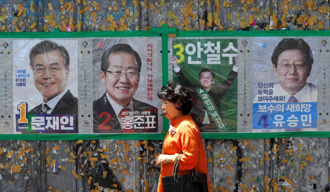 A woman walking past posters of South Korean presidential candidates. Photo: AFP