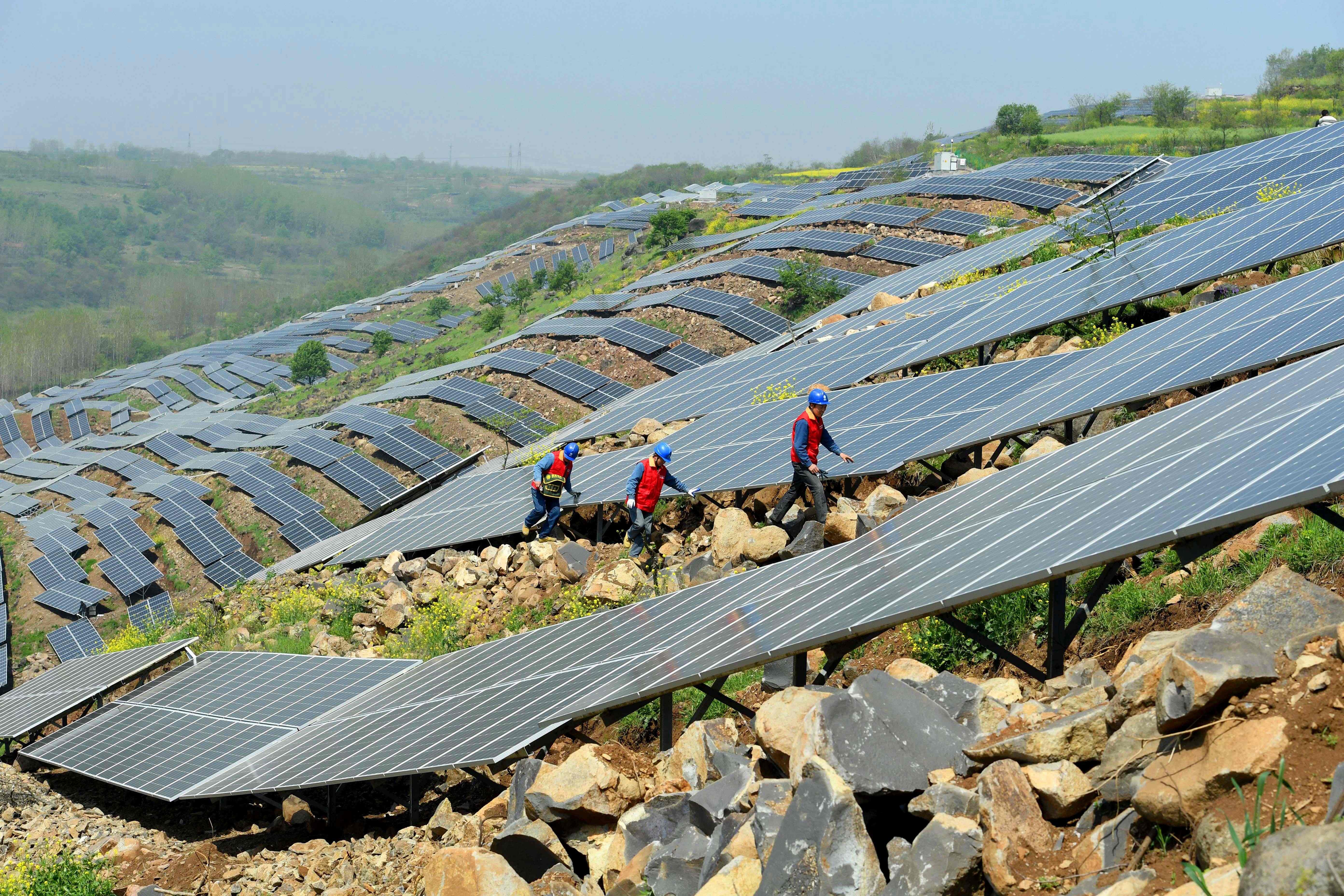 Chinese workers check solar panels last month on a hillside in a village in Chuzhou, Anhui province. China is now home to the world’s fastest-growing renewable energy industry. Photo: AFP